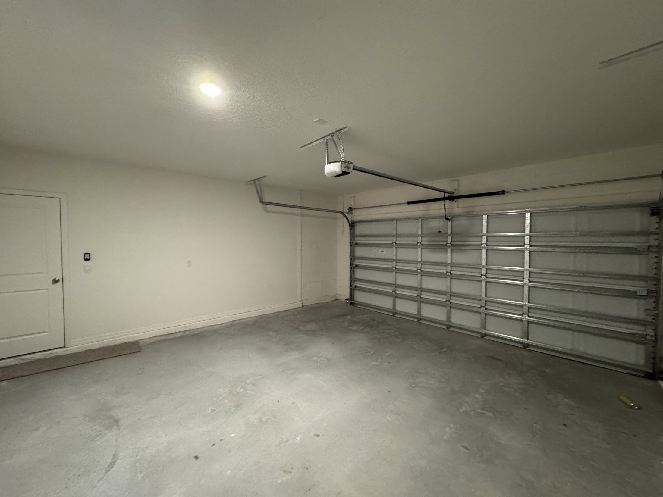 A spacious, empty garage with a closed door and a ceiling light.