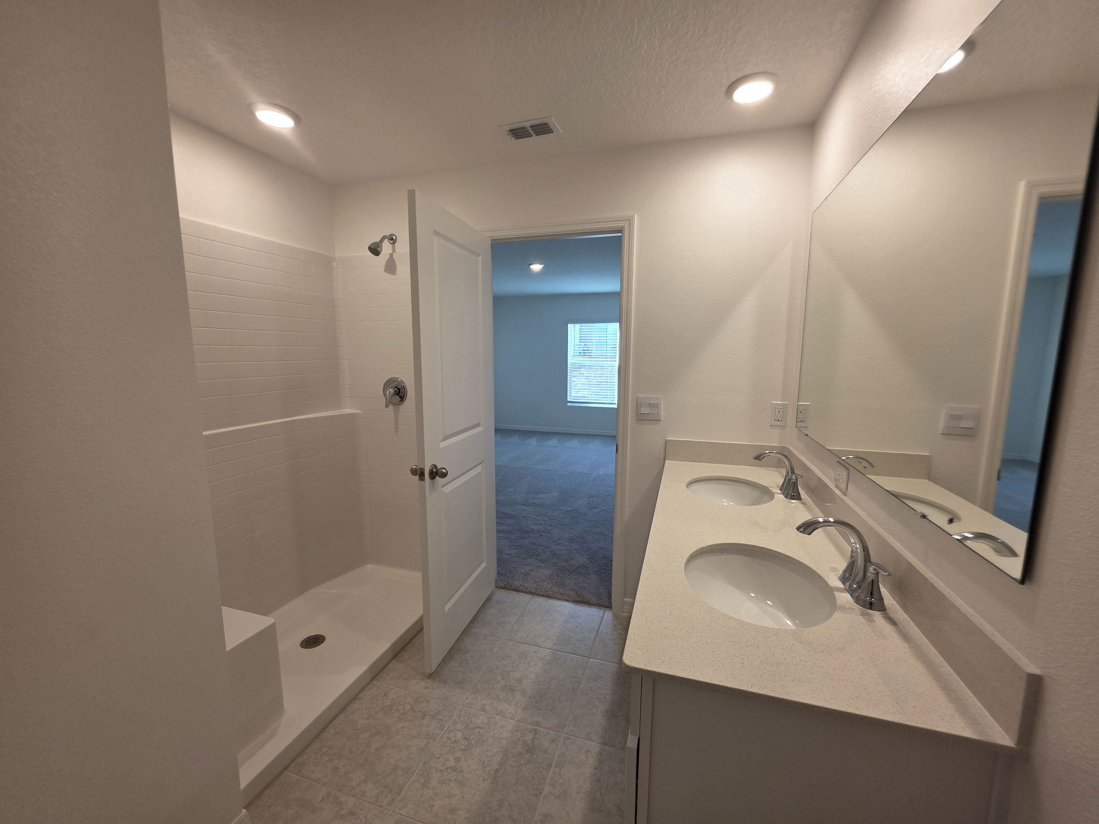 Modern bathroom featuring a walk-in shower, double vanity with sinks, and ample natural light.
