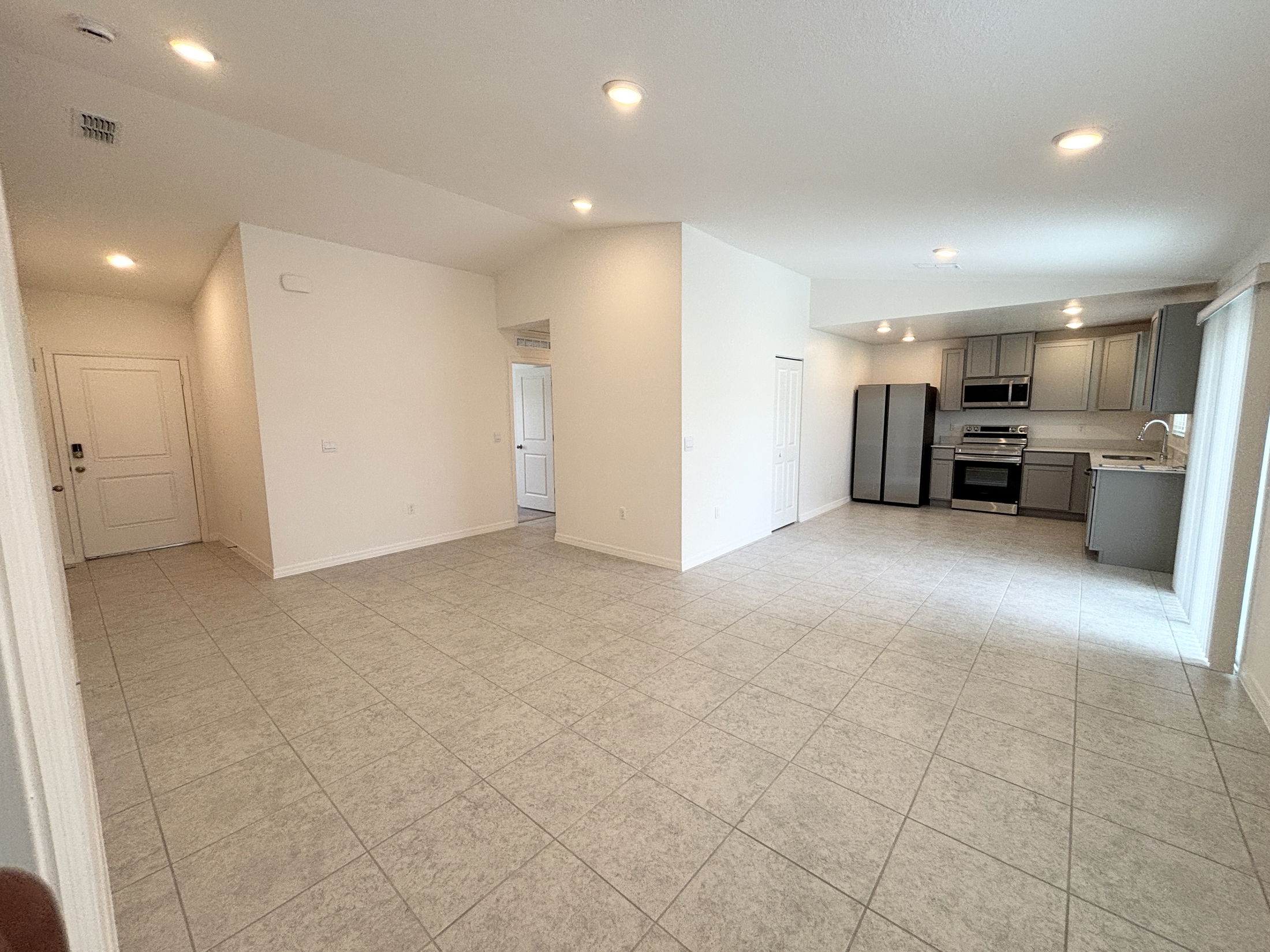 Modern open-concept kitchen and living area with tiled flooring and stainless steel appliances.