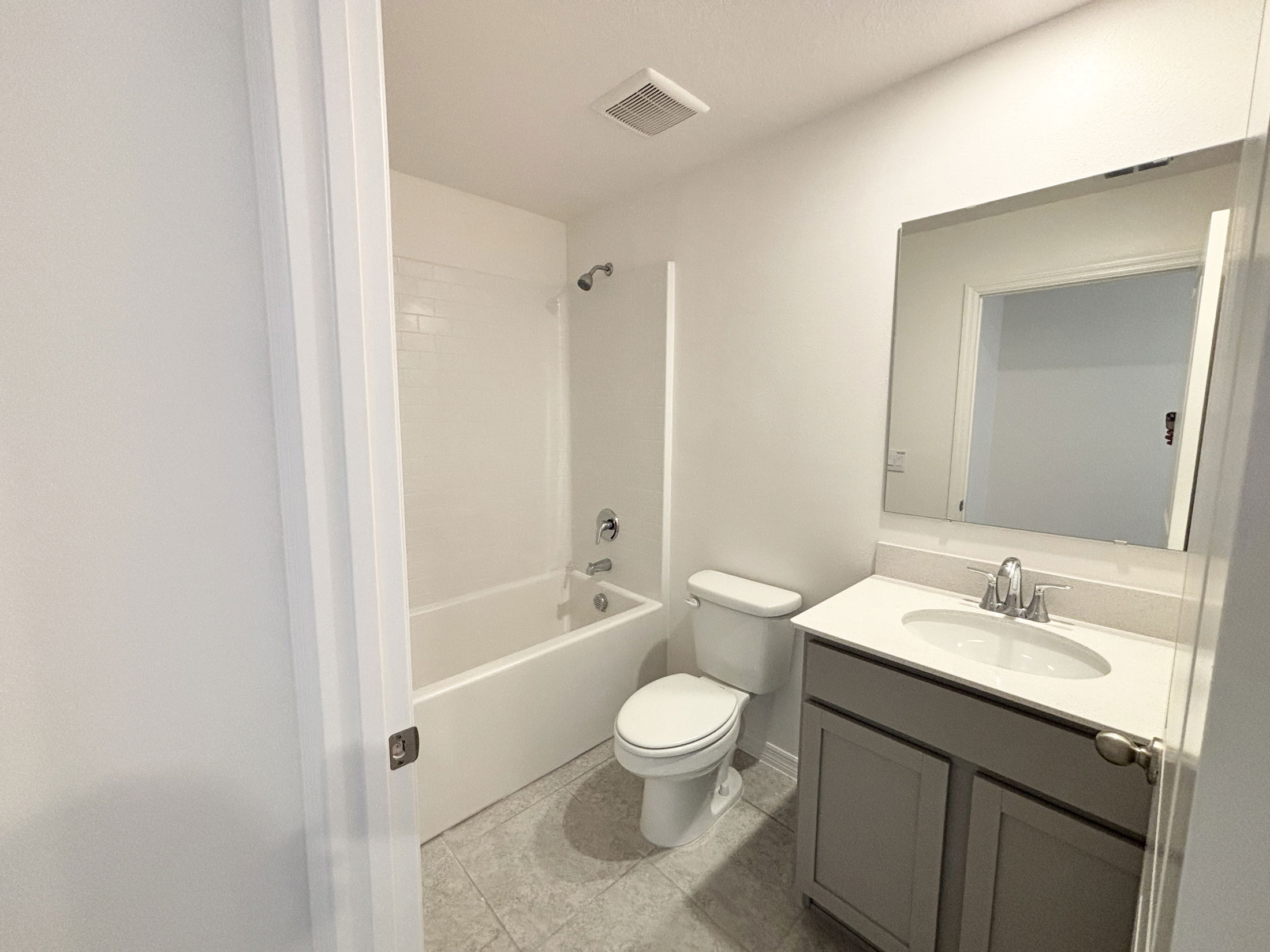 Small modern bathroom featuring a bathtub-shower combo, toilet, and a vanity sink with mirror.