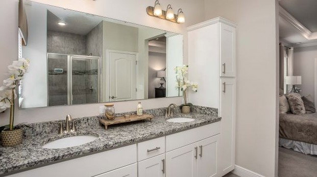 Modern bathroom with double sinks, granite countertop, and a large mirror reflecting contemporary decor.