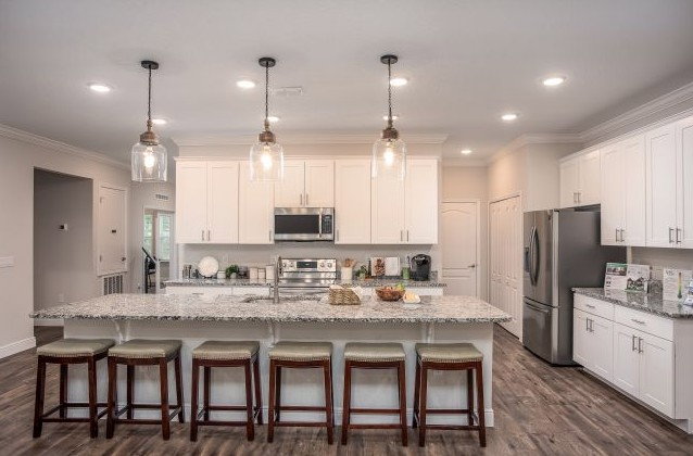 Modern kitchen with white cabinets, a large island, pendant lighting, and wooden stools.