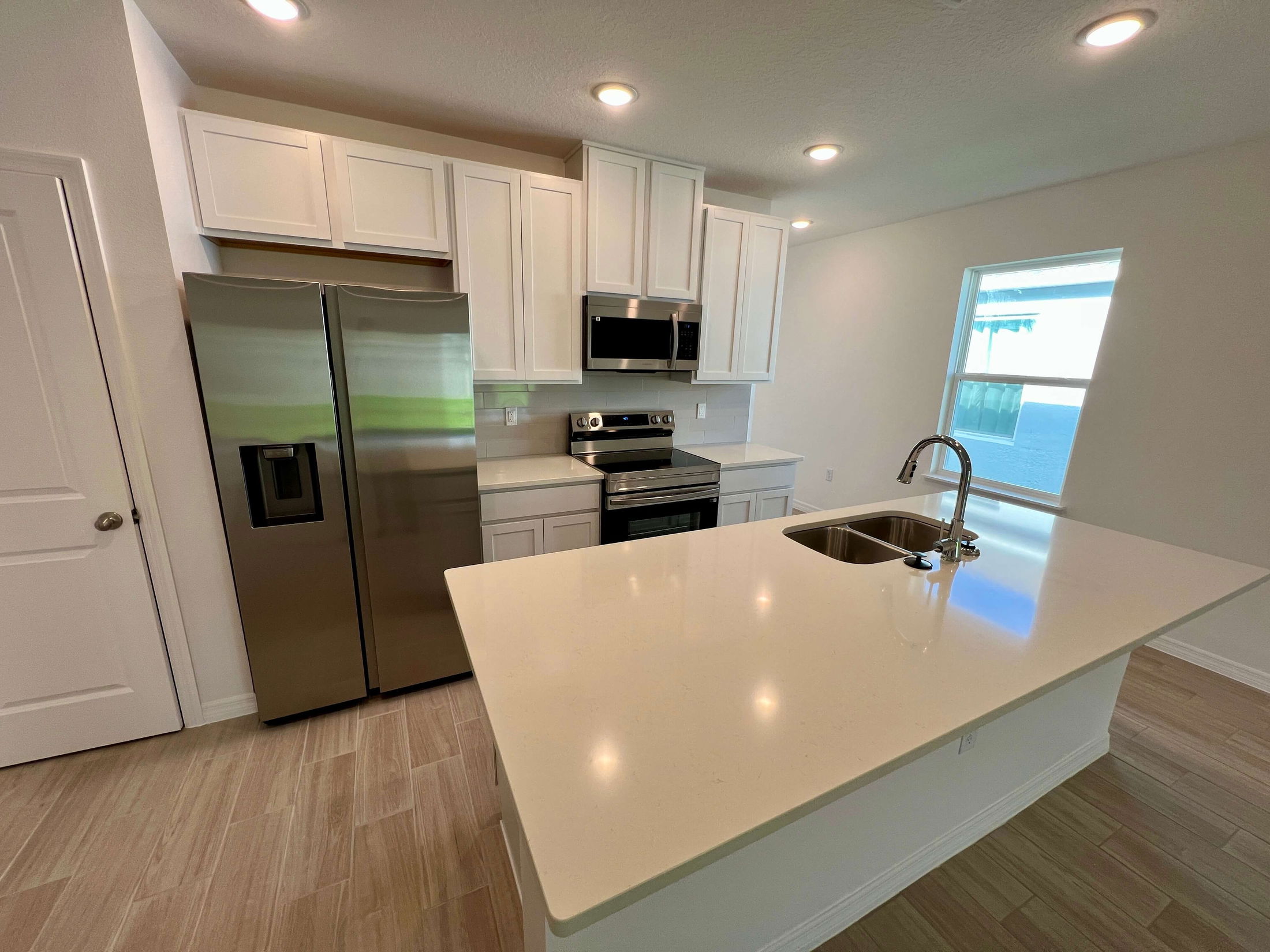 Modern kitchen with stainless steel appliances, white cabinets, and a large island with a built-in sink.