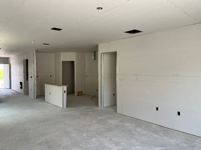 Unfinished interior space with drywall installation and exposed concrete flooring.