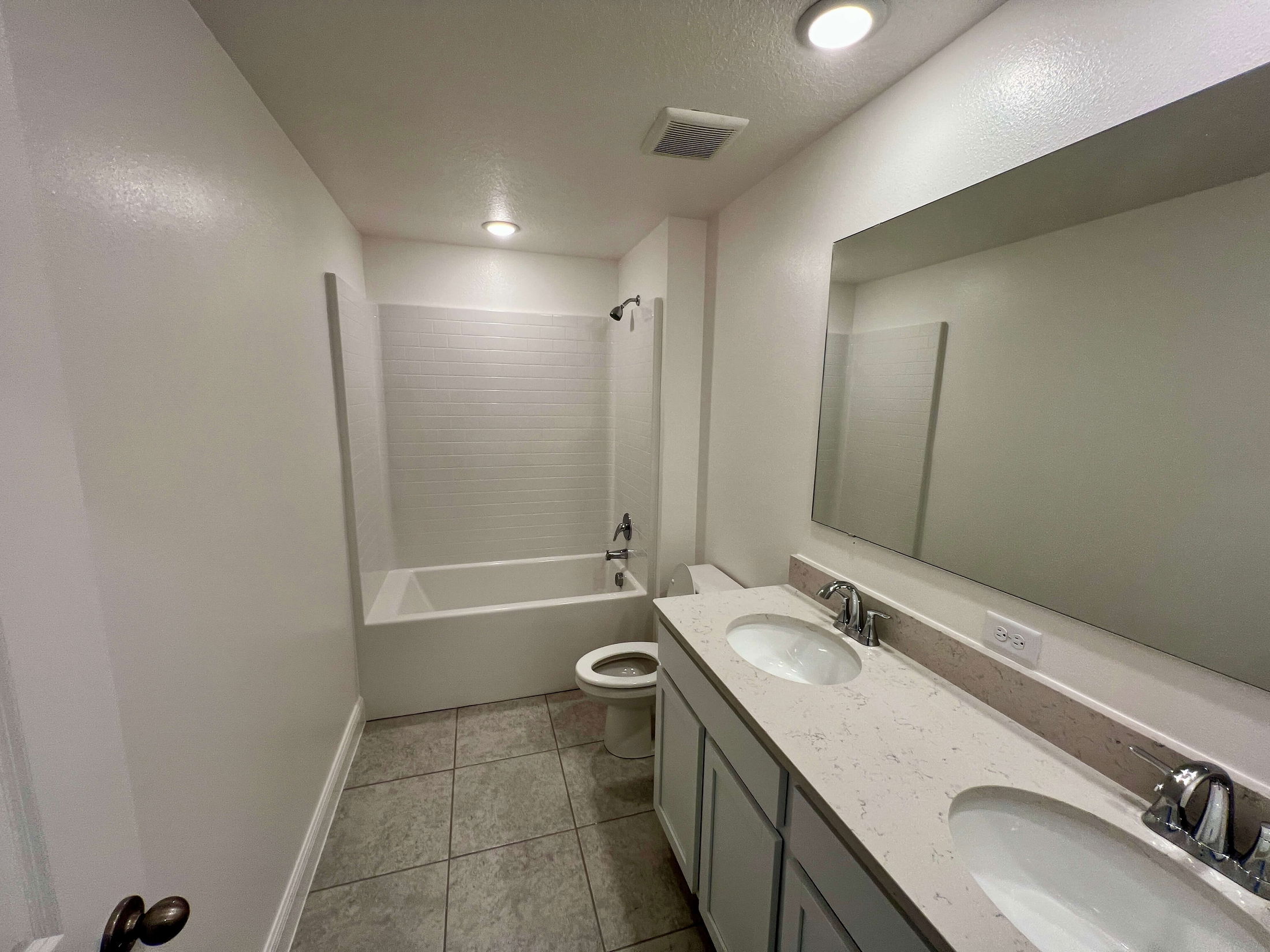 Modern bathroom with a spacious white vanity, double sinks, and a shower-tub combo.
