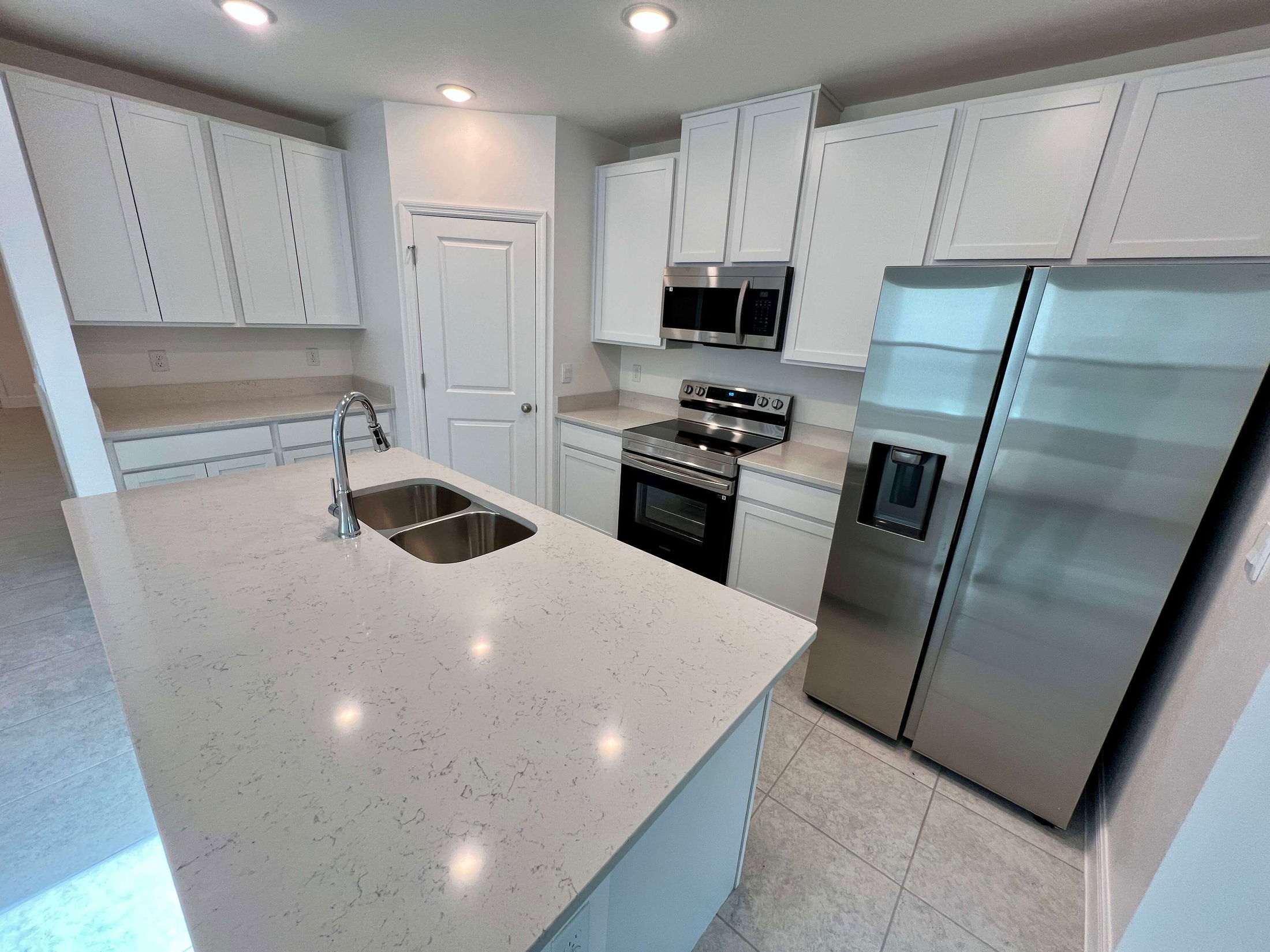 Modern kitchen with white cabinets, stainless steel appliances, and a sleek quartz countertop island.