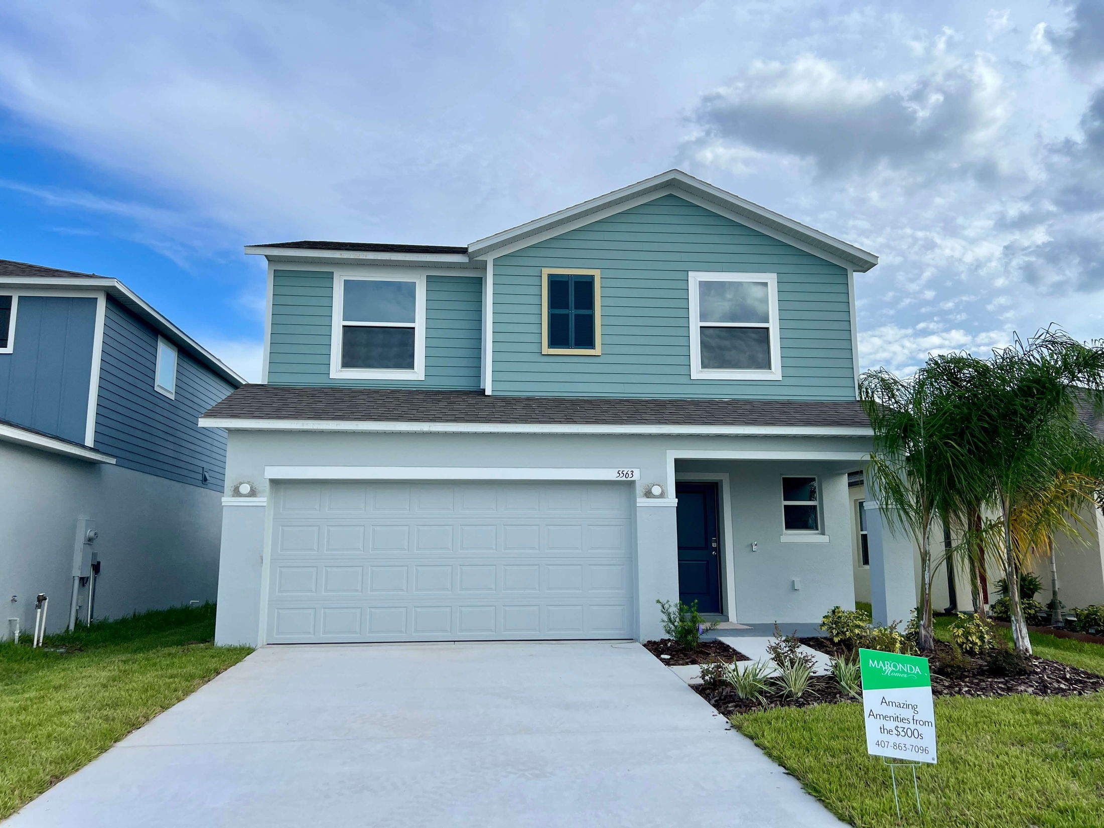 Contemporary blue two-story house with garage and landscaped front yard, featuring a sales sign from Maronda Homes.