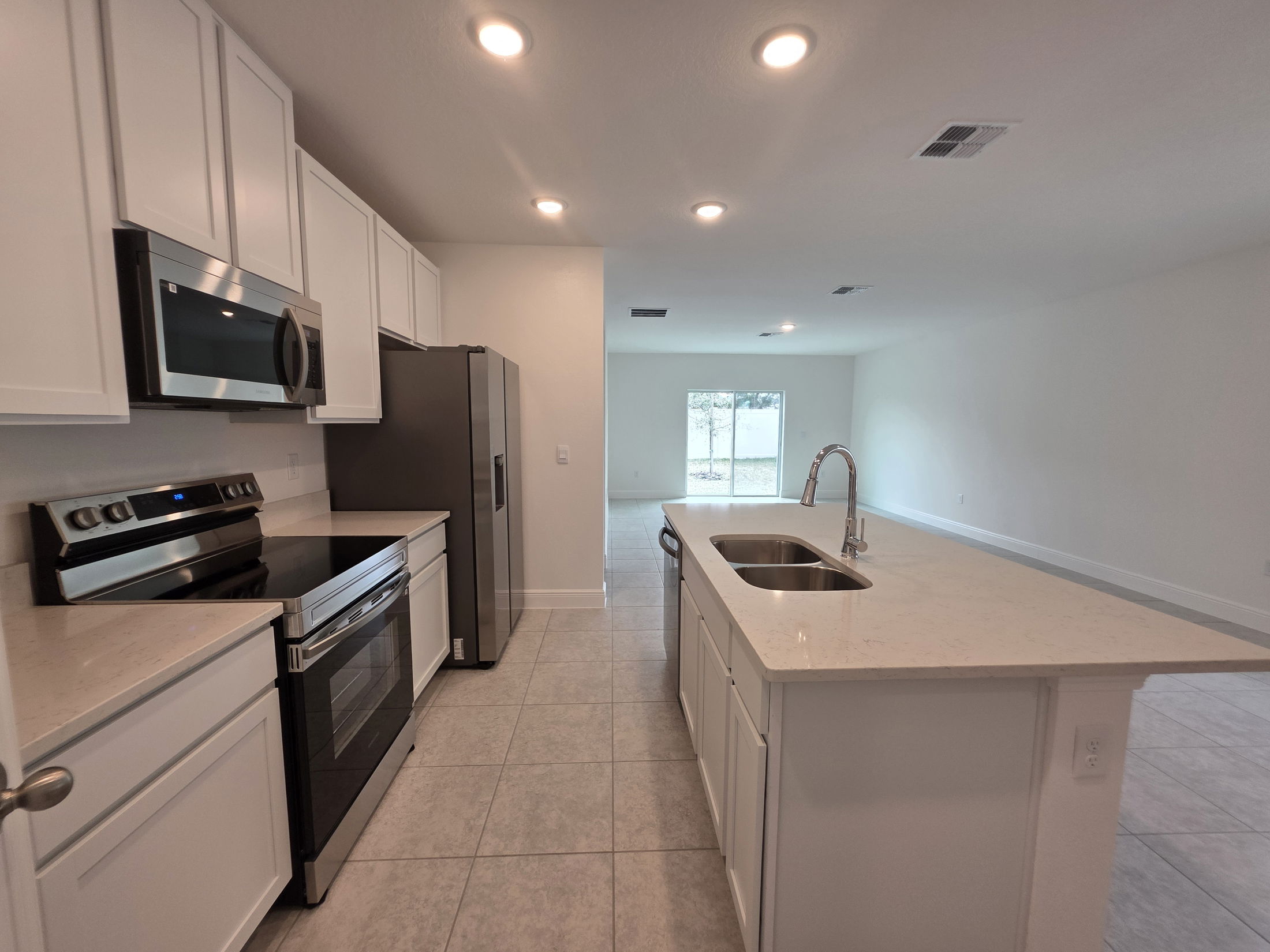 Modern kitchen interior featuring stainless steel appliances, white cabinetry, and a spacious island with a sink.