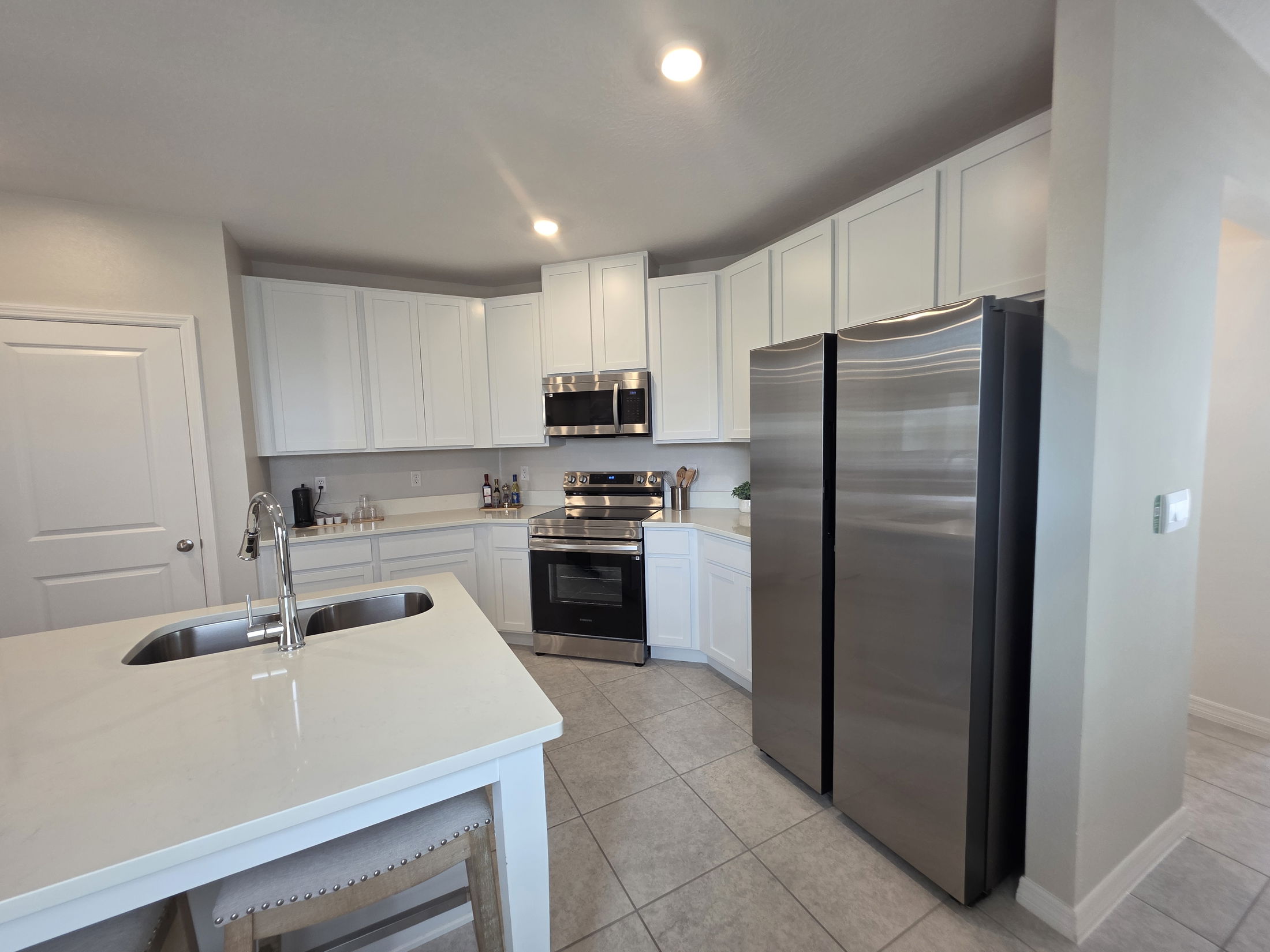 Modern kitchen with white cabinets, stainless steel appliances, and a spacious island featuring a sink.