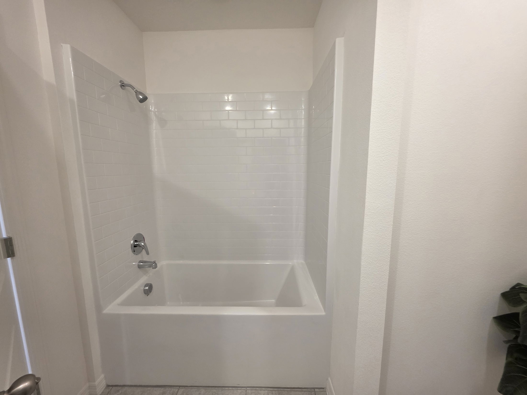 Modern bathroom featuring a white tiled shower and bathtub combination with polished chrome fixtures.