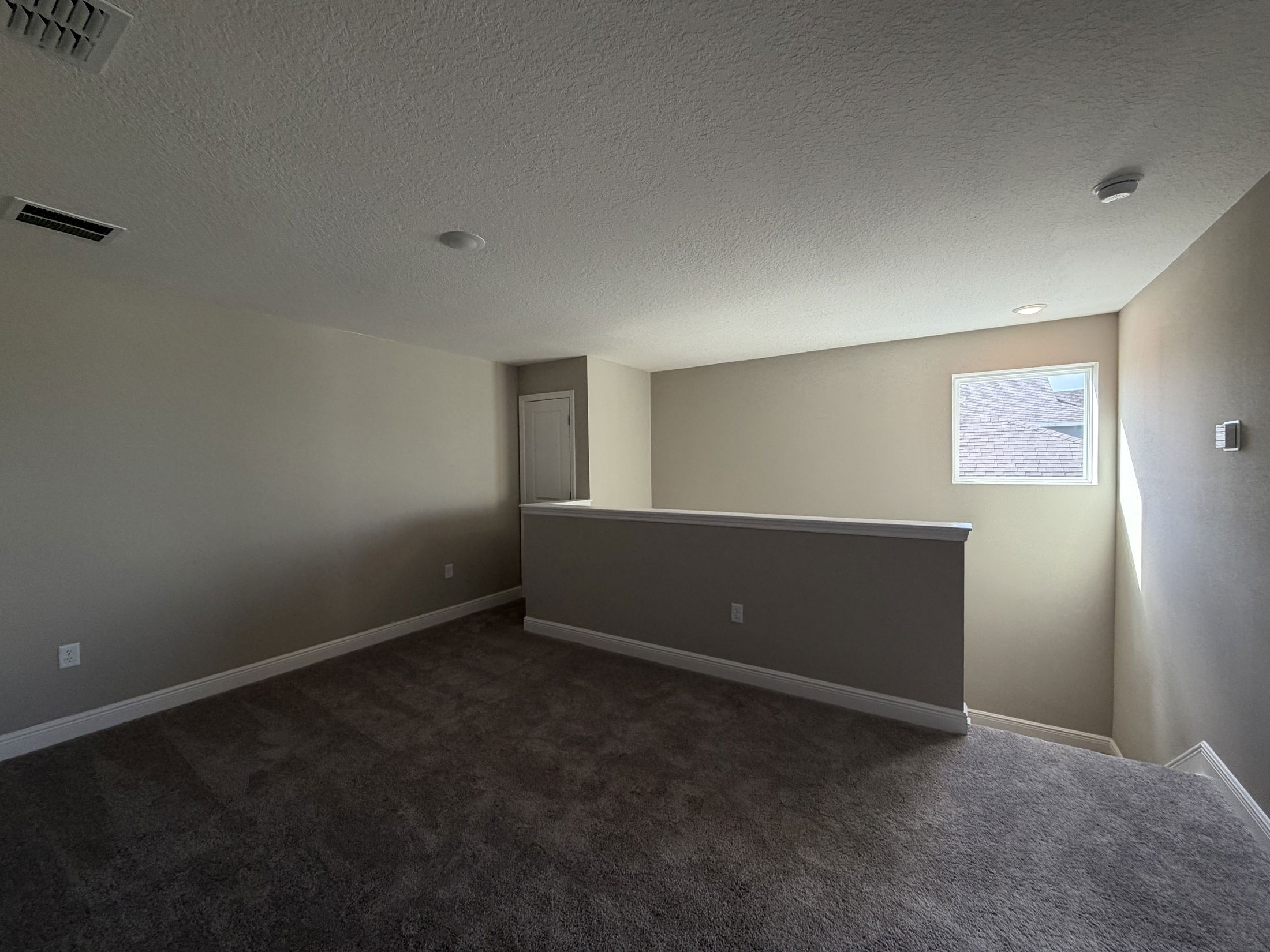 Spacious, well-lit upstairs loft area featuring neutral walls and plush carpeting.