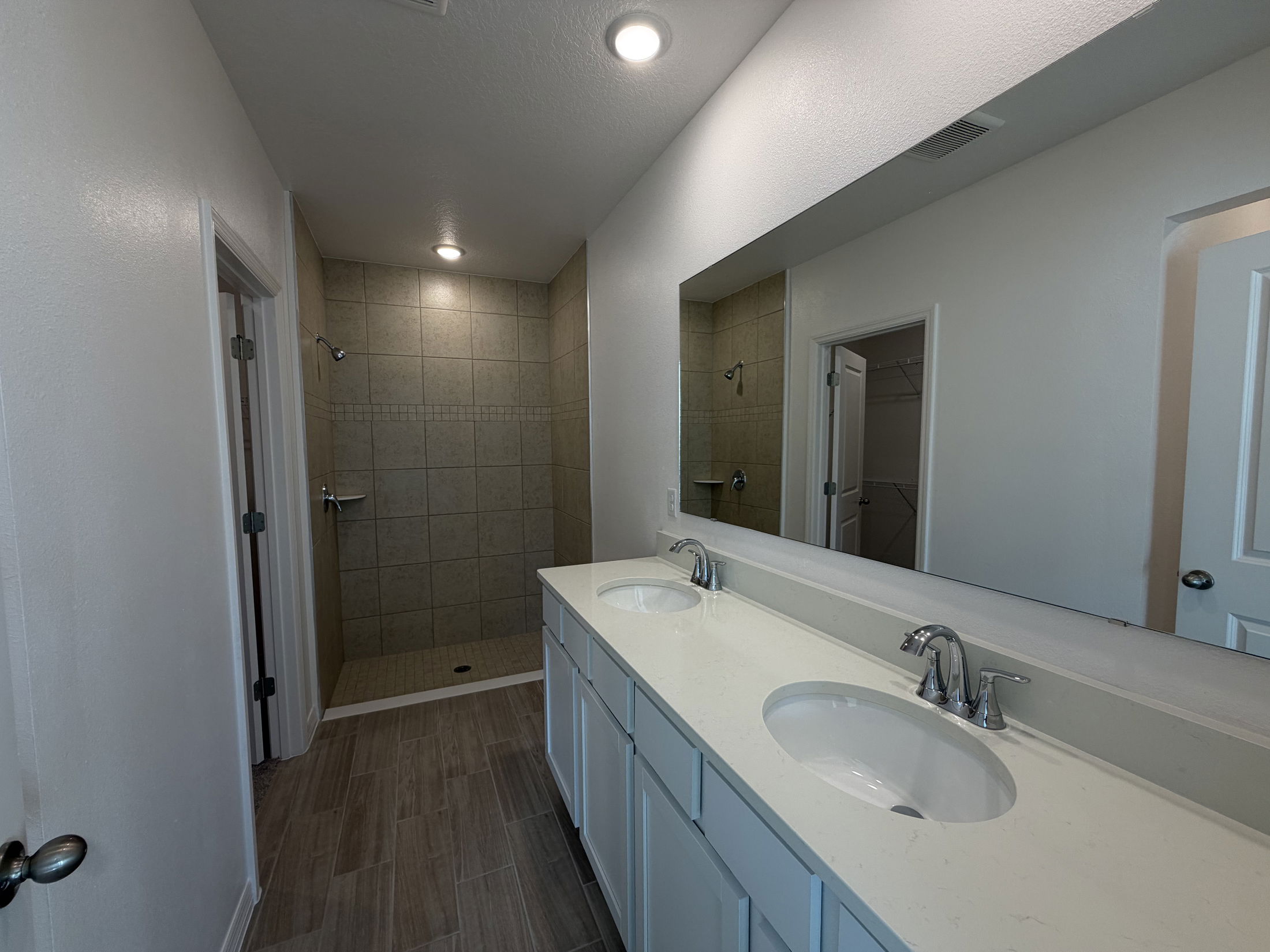 Spacious modern bathroom featuring double sinks, a walk-in shower, and elegant tile accents.