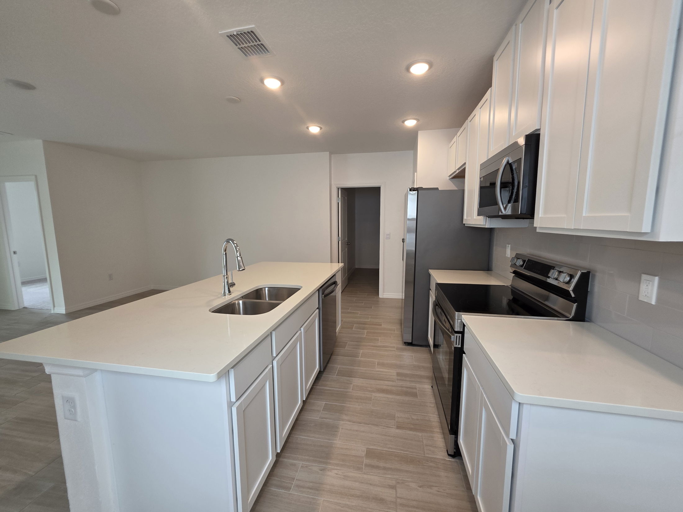 Modern kitchen with white cabinets, stainless steel appliances, and a large island with a double sink.