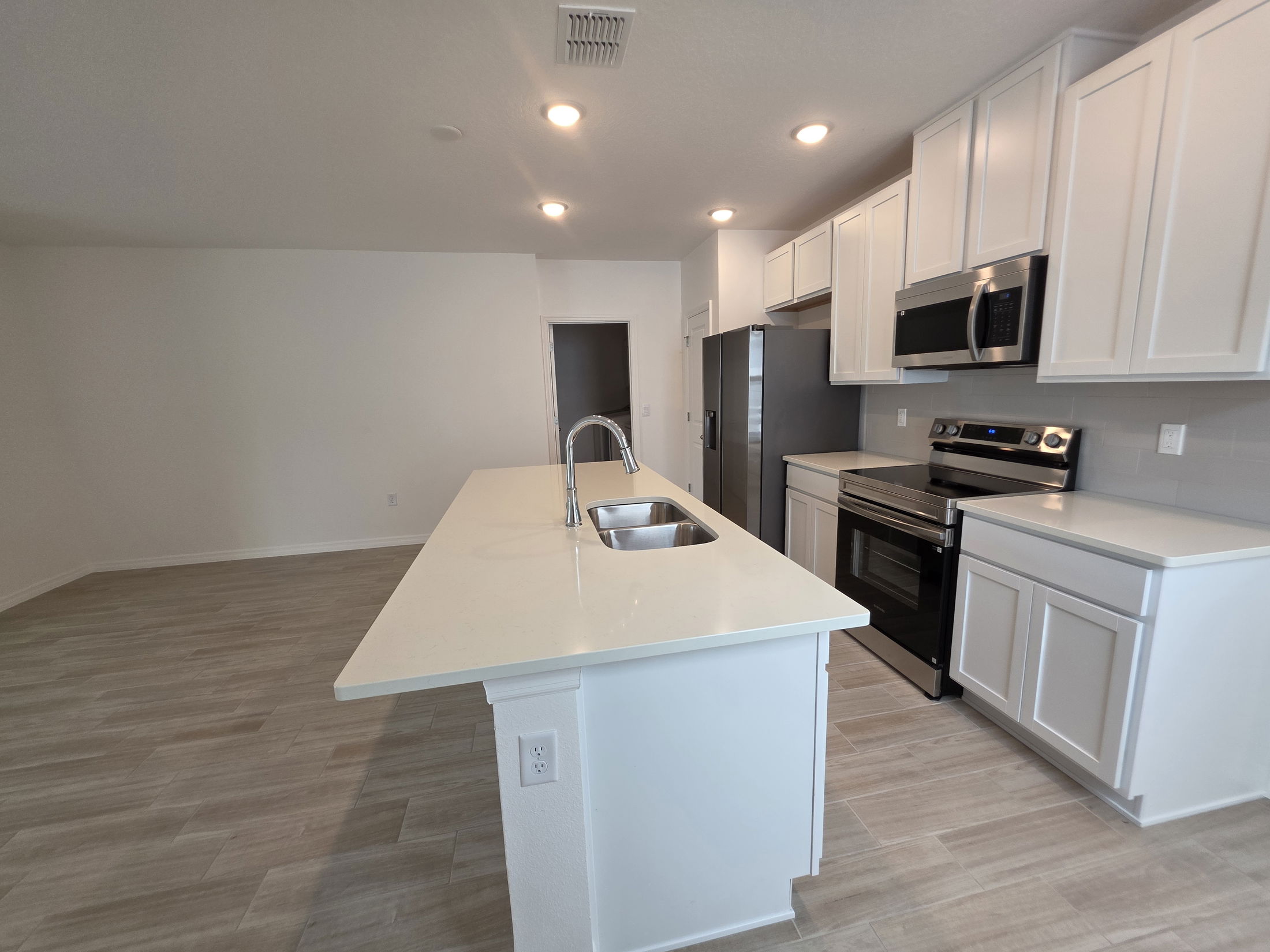 Modern kitchen interior featuring white cabinetry, stainless steel appliances, and a spacious island.