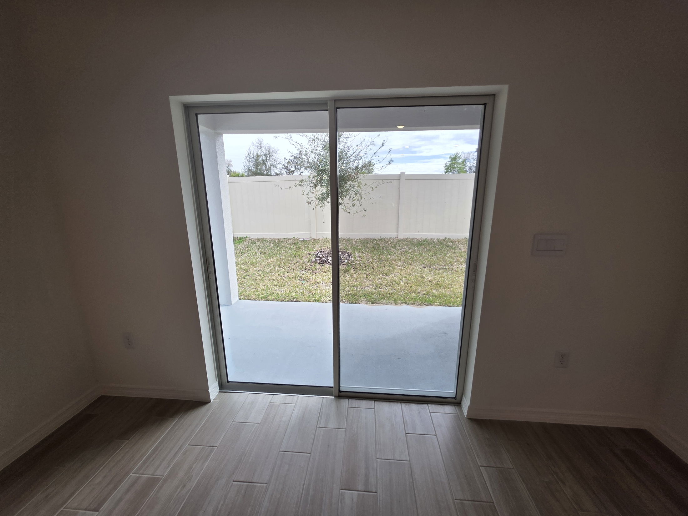 Interior view of a modern room featuring sliding glass doors leading to a private outdoor space with a garden.