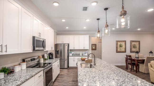 Modern kitchen with white cabinets, granite countertops, stainless steel appliances, and pendant lighting.