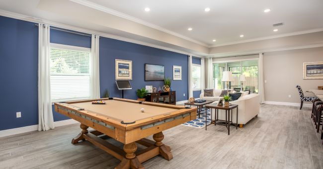 Contemporary living room with a pool table, elegant seating area, and a mix of blue and neutral decor.