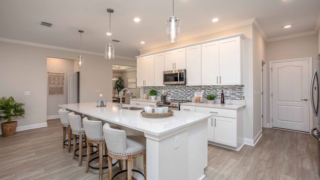 Modern kitchen with a white countertop island, bar stools, pendant lighting, and sleek cabinetry.