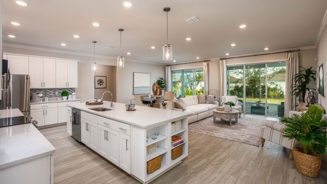 Modern open-concept kitchen and living room with white cabinetry, a large island, and floor-to-ceiling windows.