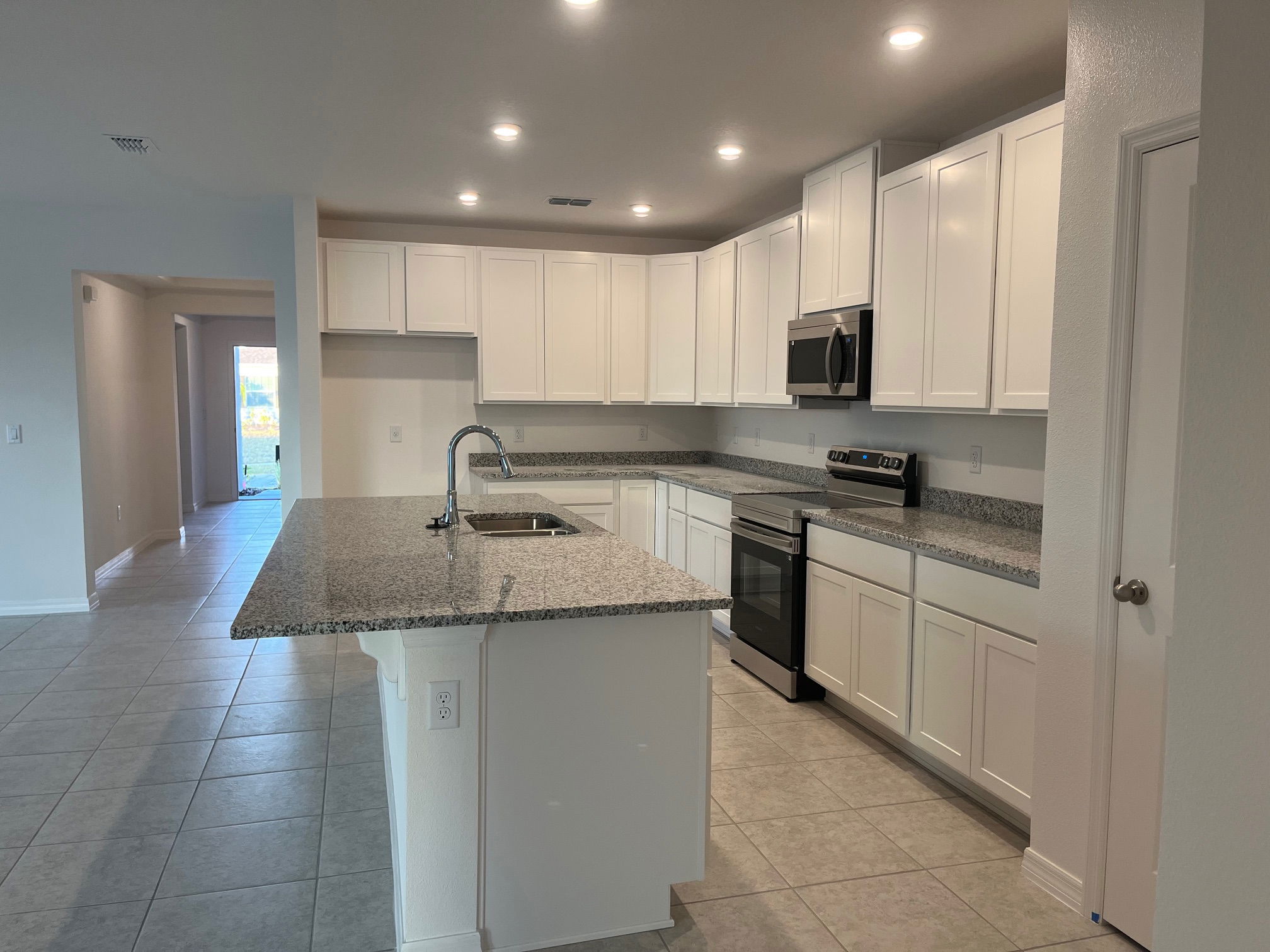Modern kitchen with white cabinets, granite countertops, stainless steel appliances, and recessed lighting.
