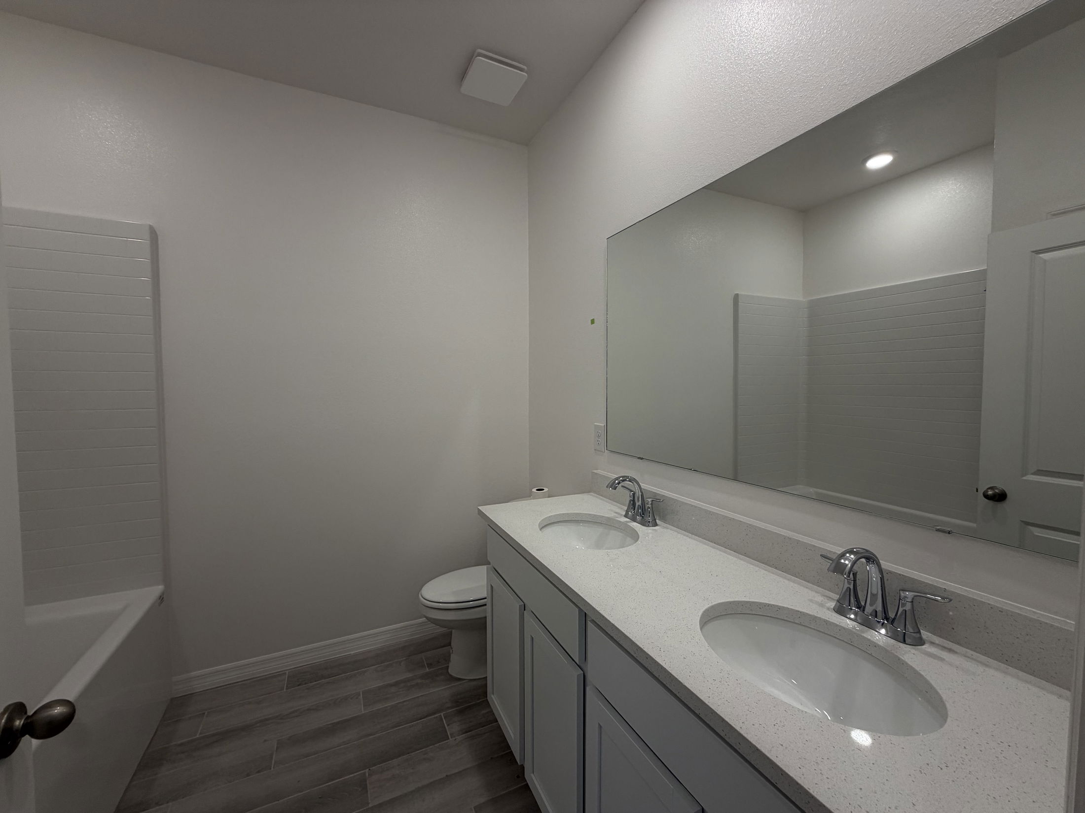 Modern bathroom featuring a double vanity with oval sinks, a large mirror, and a shower-bathtub combination.