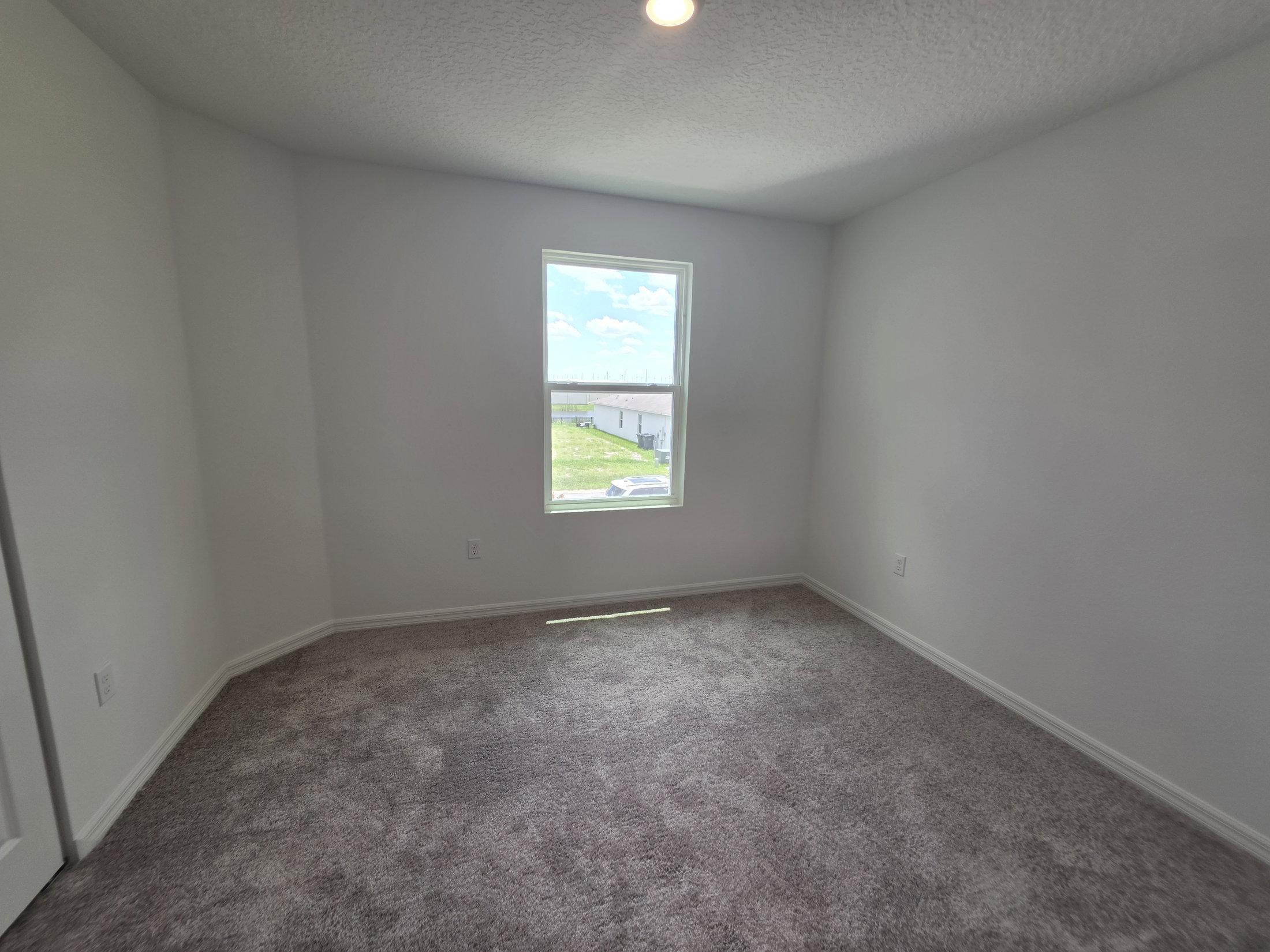 Empty room with light gray carpet and a window allowing natural light.