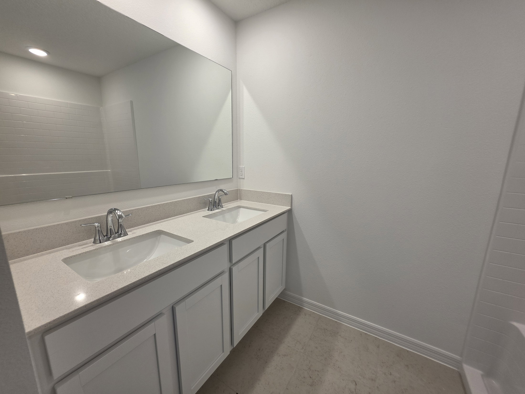 Modern bathroom featuring a double sink vanity with a large mirror and light-colored walls.