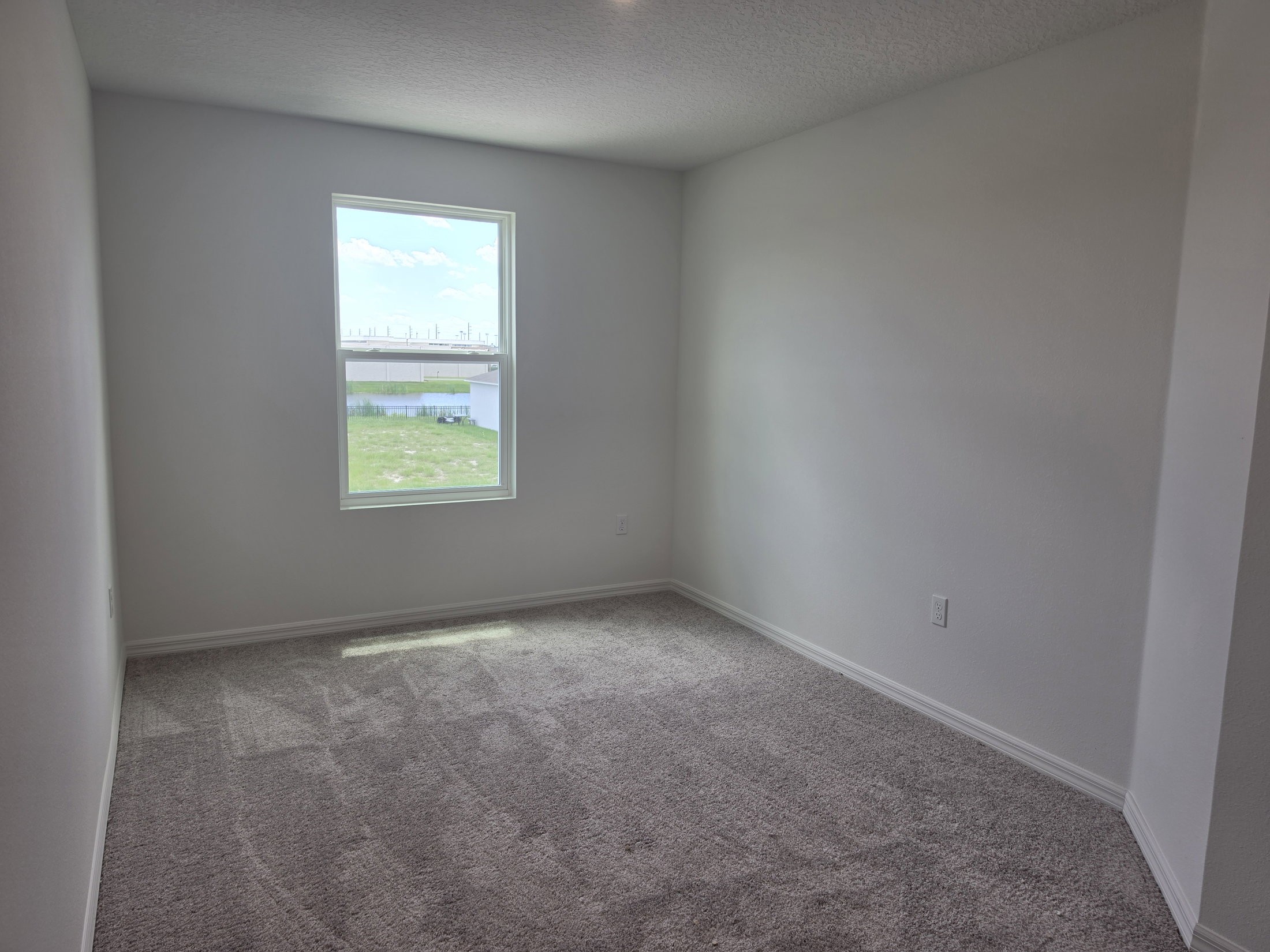 Empty room with light gray carpet and a window allowing natural light.