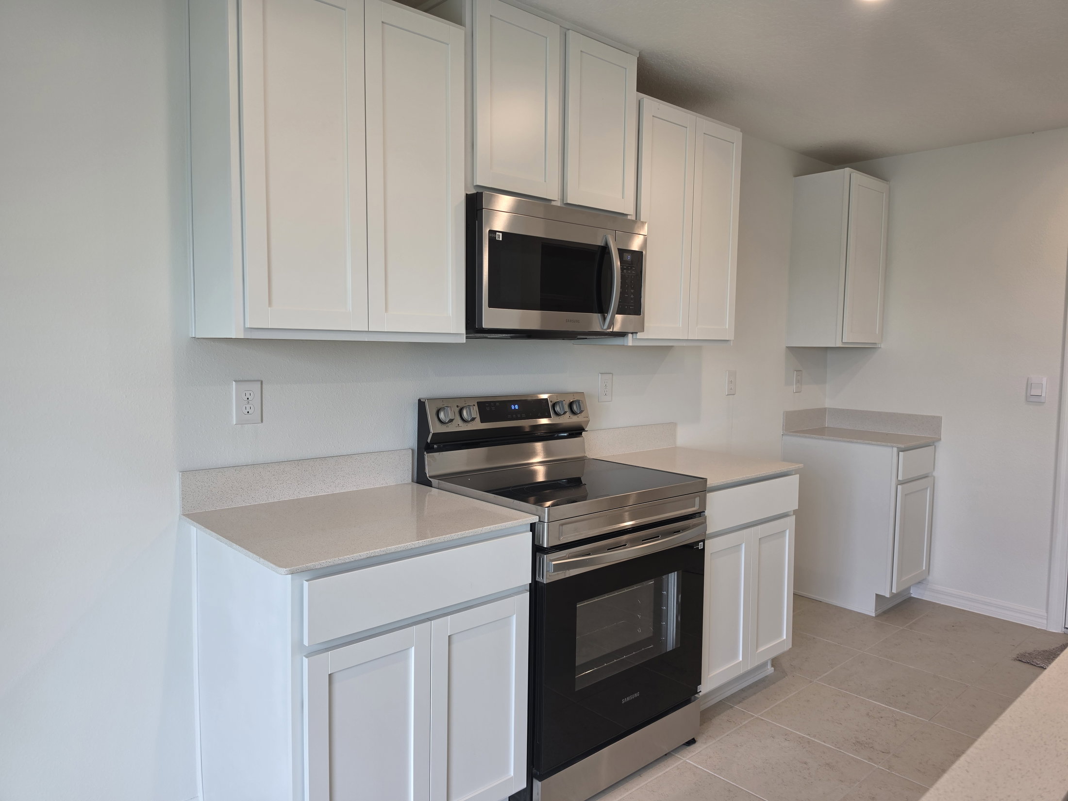 Modern kitchen with white cabinetry, stainless steel appliances, and light-colored countertops.
