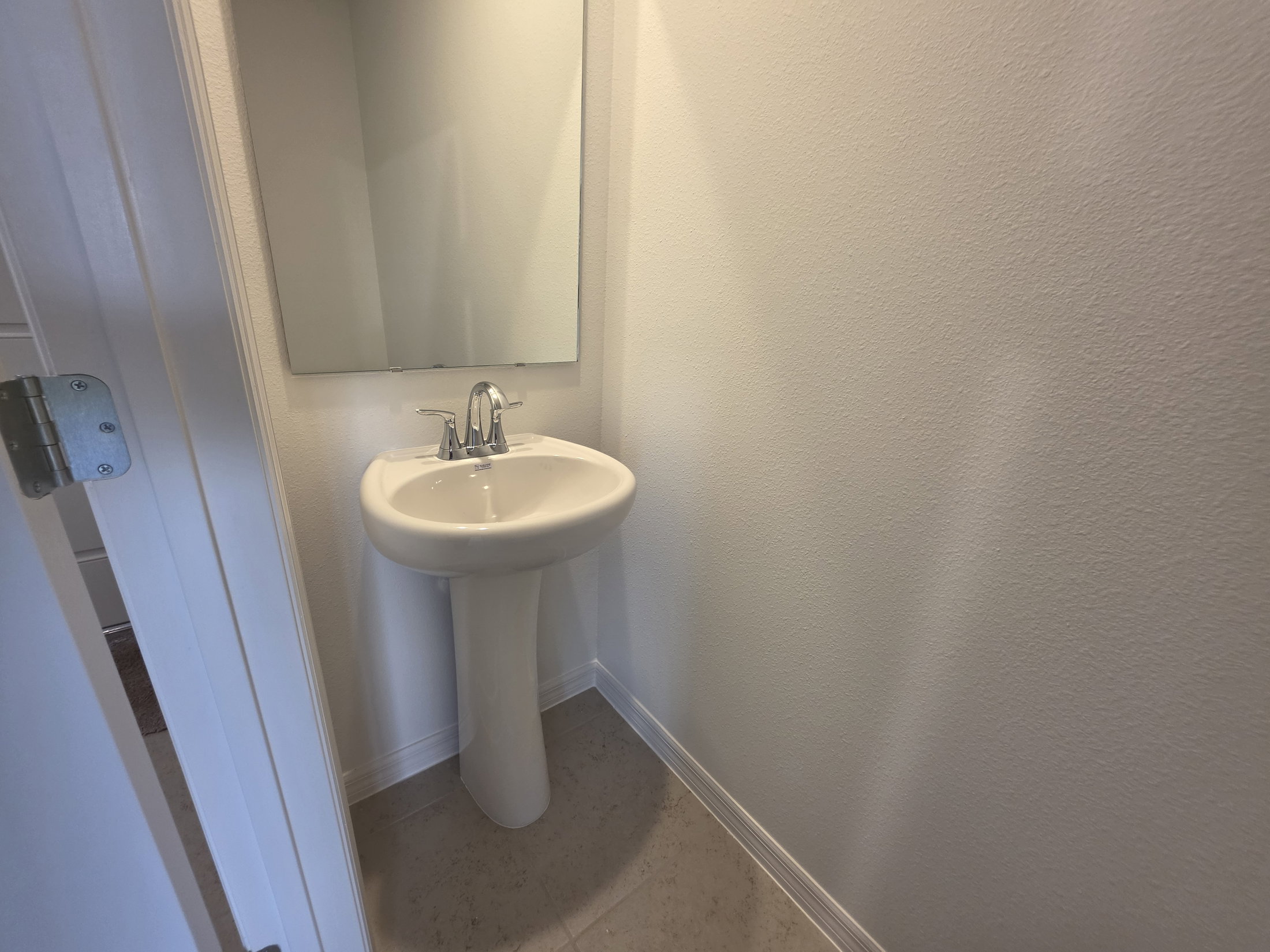 Small bathroom with a pedestal sink and a mirror on the wall.