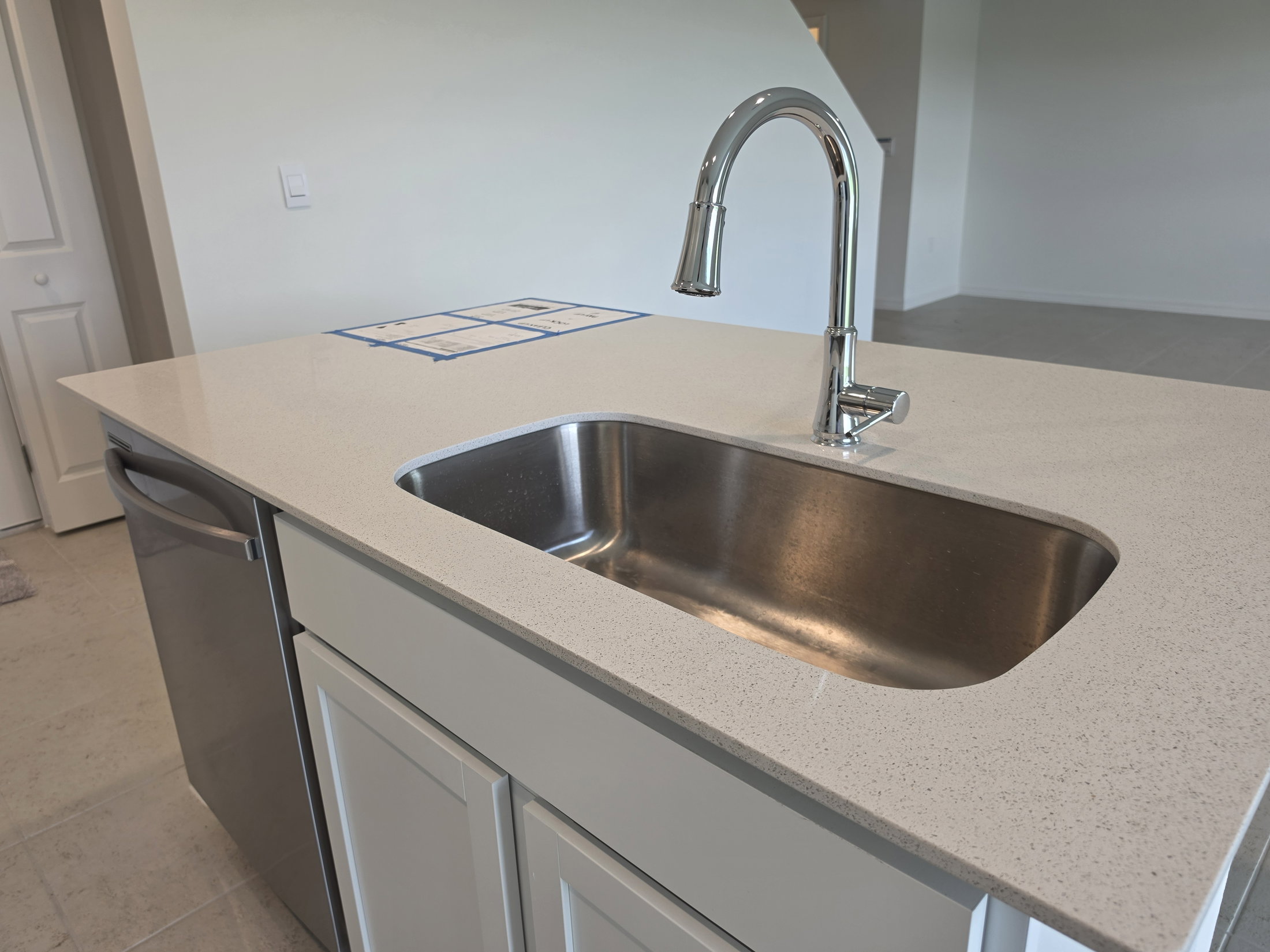 A modern kitchen sink with a stainless steel basin and a polished chrome faucet, set against a light-colored countertop.