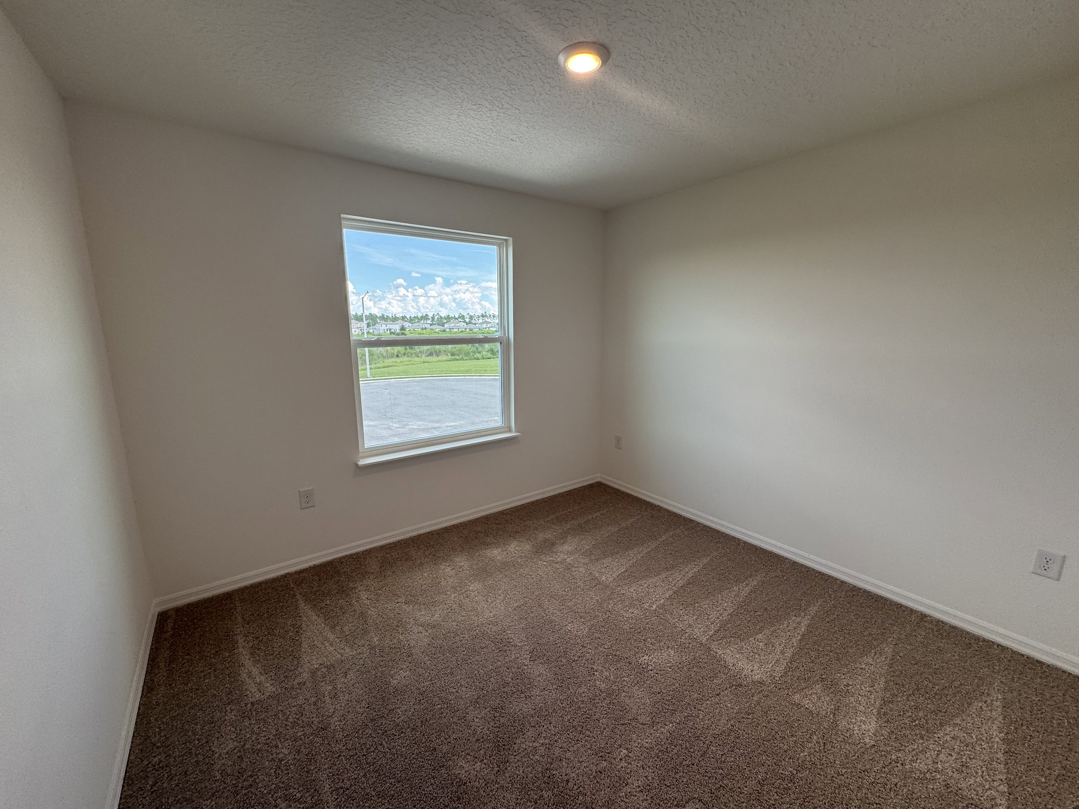 Empty room with carpeted floor and a window providing natural light.