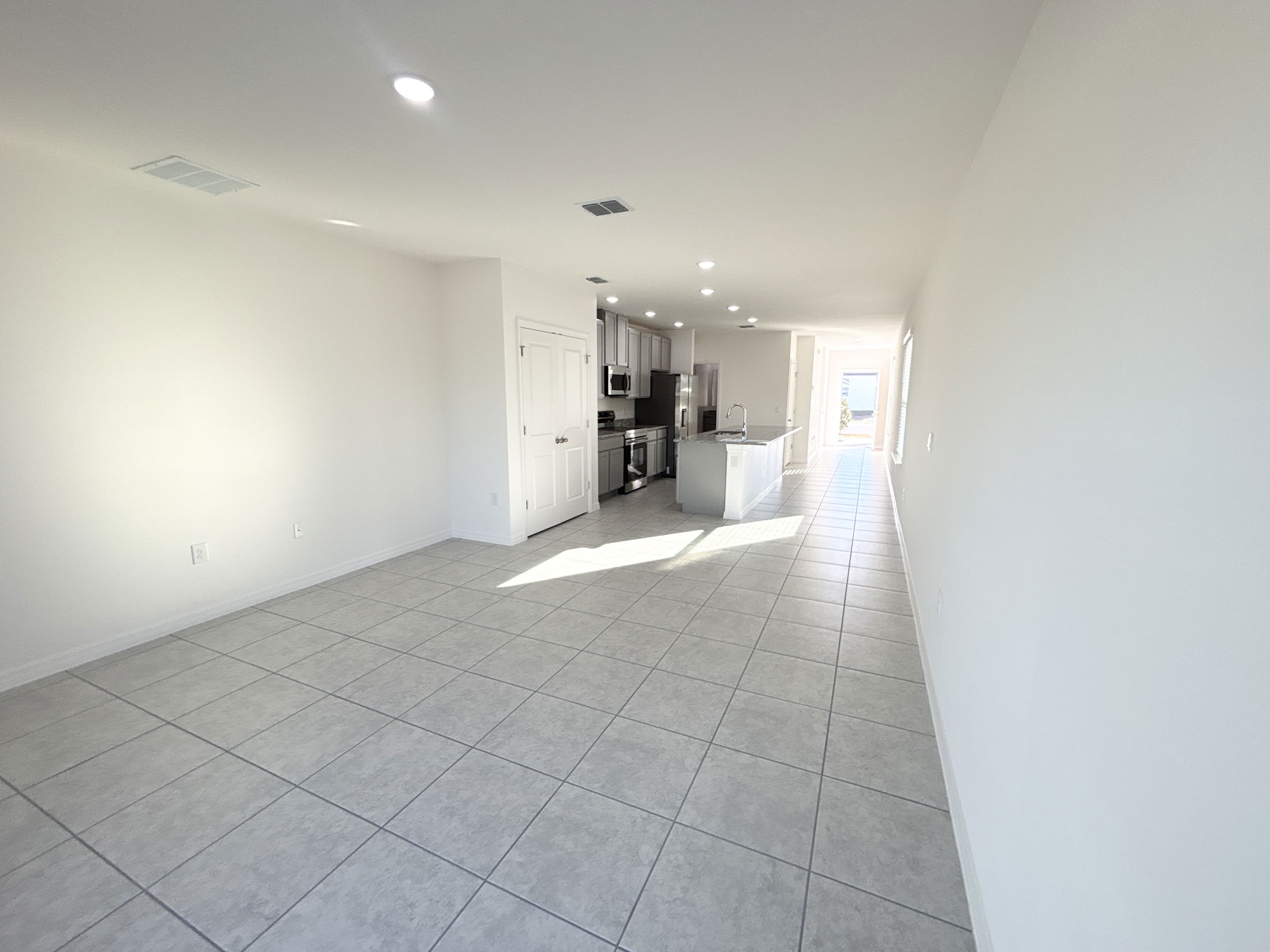 Spacious modern kitchen and living area with tile flooring and natural light.