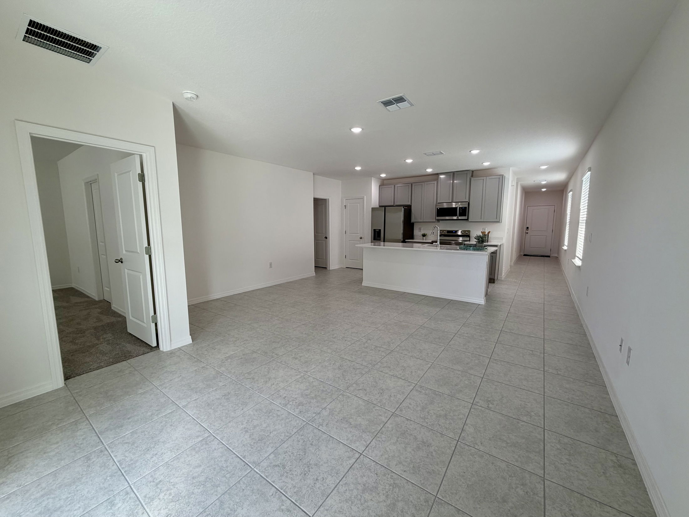 Spacious open-concept kitchen and living area with modern appliances, tile flooring, and abundant natural light.