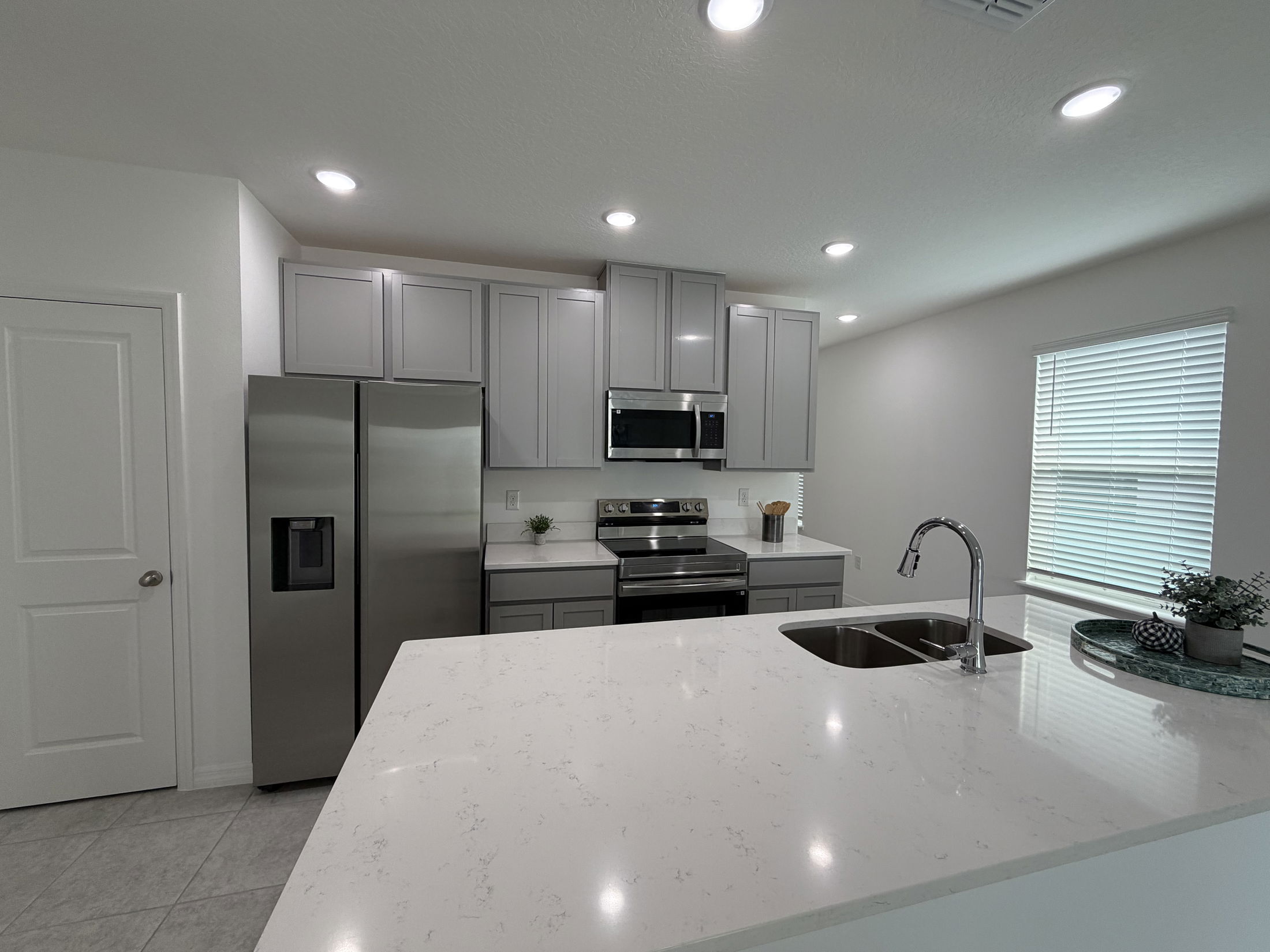Modern kitchen with sleek gray cabinets, stainless steel appliances, and a spacious white marble island countertop.