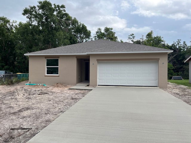 Newly constructed single-story suburban home with a two-car garage and fresh driveway in a landscaped yard setting.