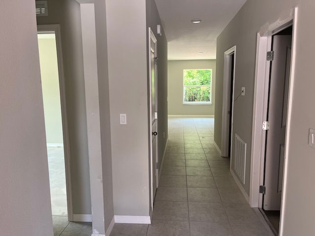 Bright hallway view of a modern home interior with gray tile flooring and light gray walls.