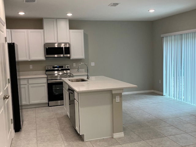 Modern kitchen with white cabinetry, stainless steel appliances, and tile flooring featuring a central island and sliding glass door.