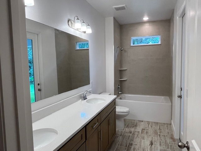 Modern bathroom with double sink vanity, bathtub, wooden cabinetry, and tiled flooring.