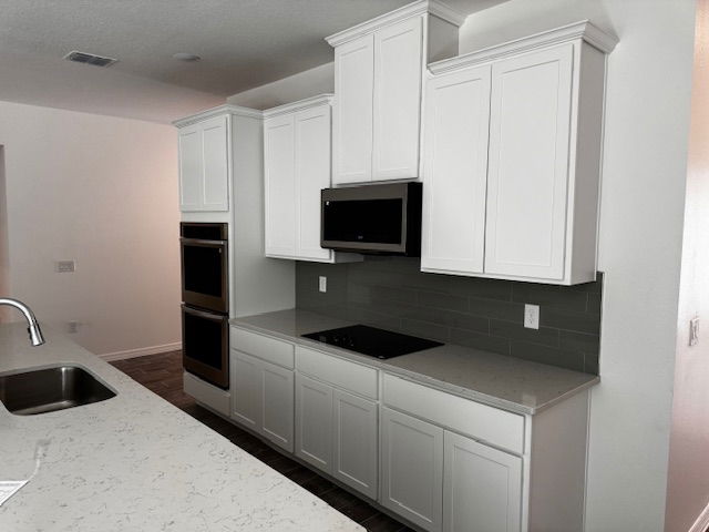 Modern kitchen with white cabinets, integrated oven, microwave, and sleek countertop.