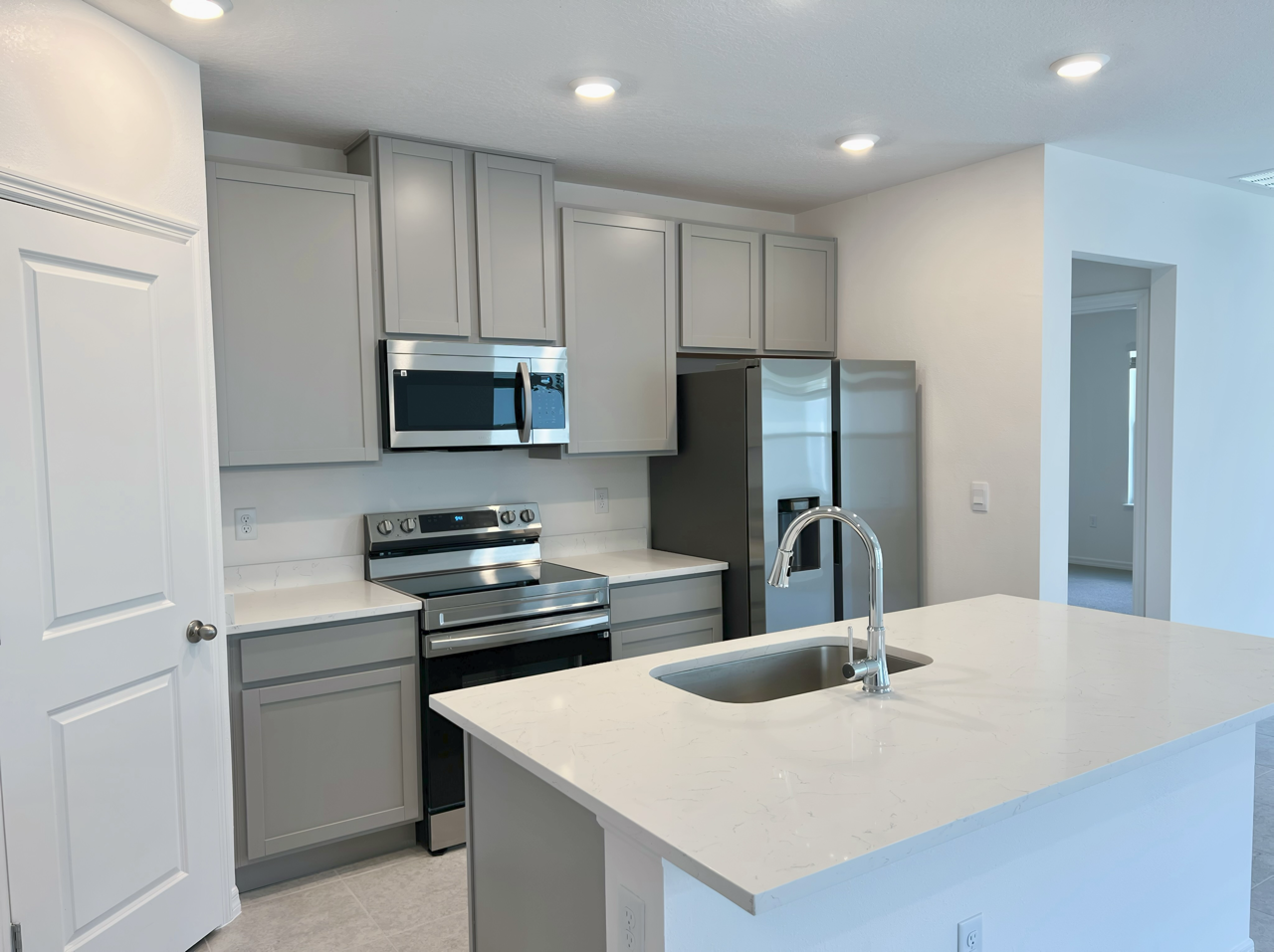 Modern kitchen interior with gray cabinetry, stainless steel appliances, and a sleek island countertop.