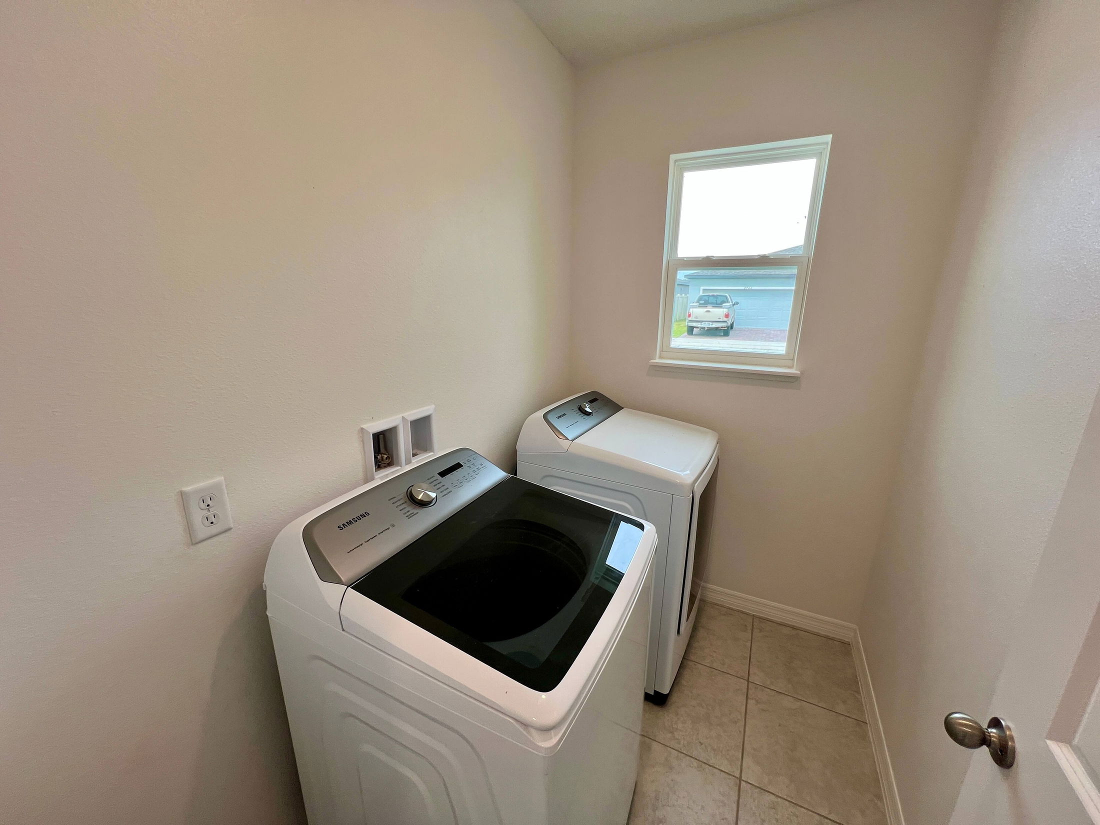 Modern laundry room featuring a Samsung washer and dryer set under a small window.