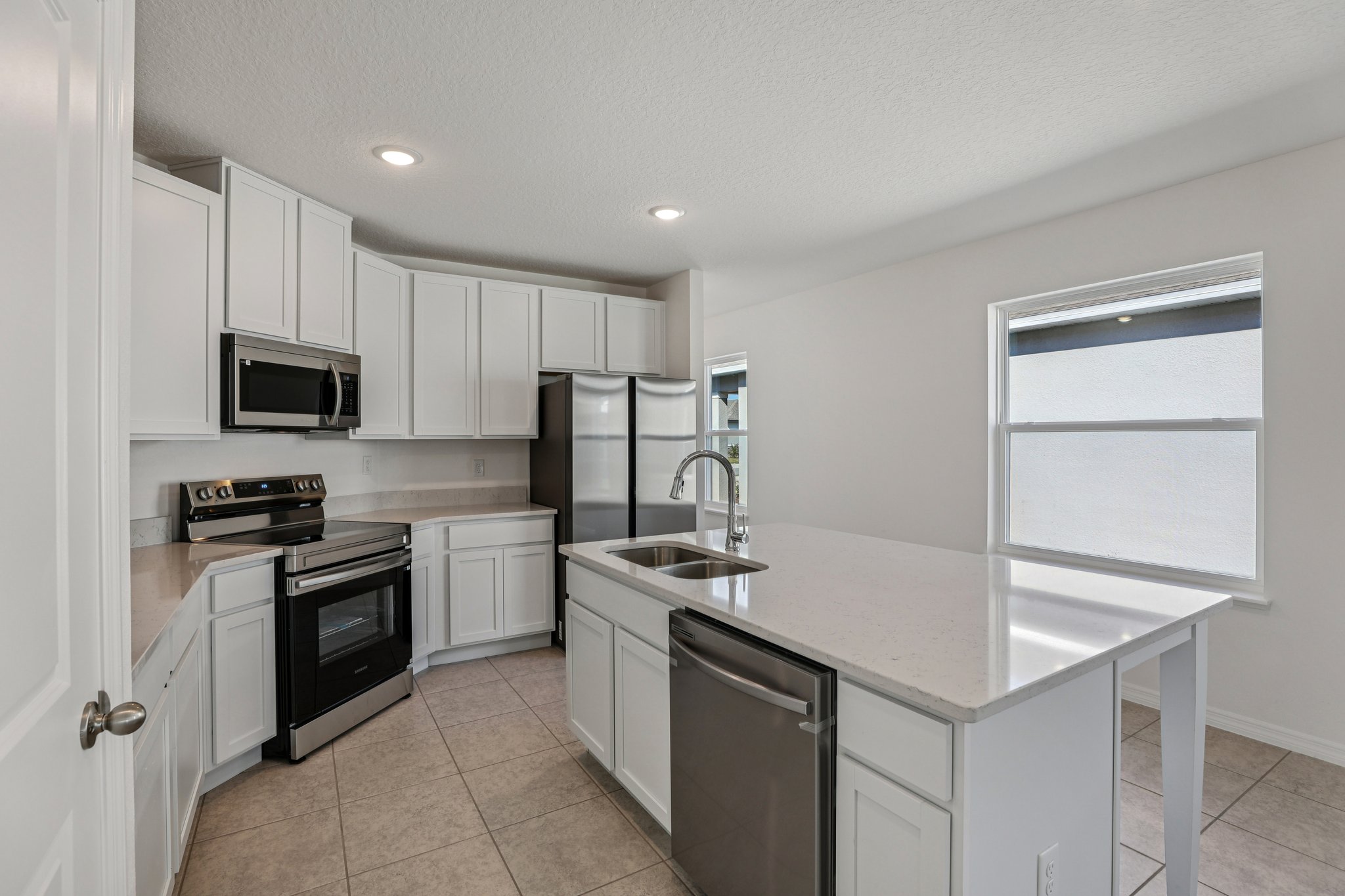 Modern kitchen with white cabinets, stainless steel appliances, and a large central island with a sink.