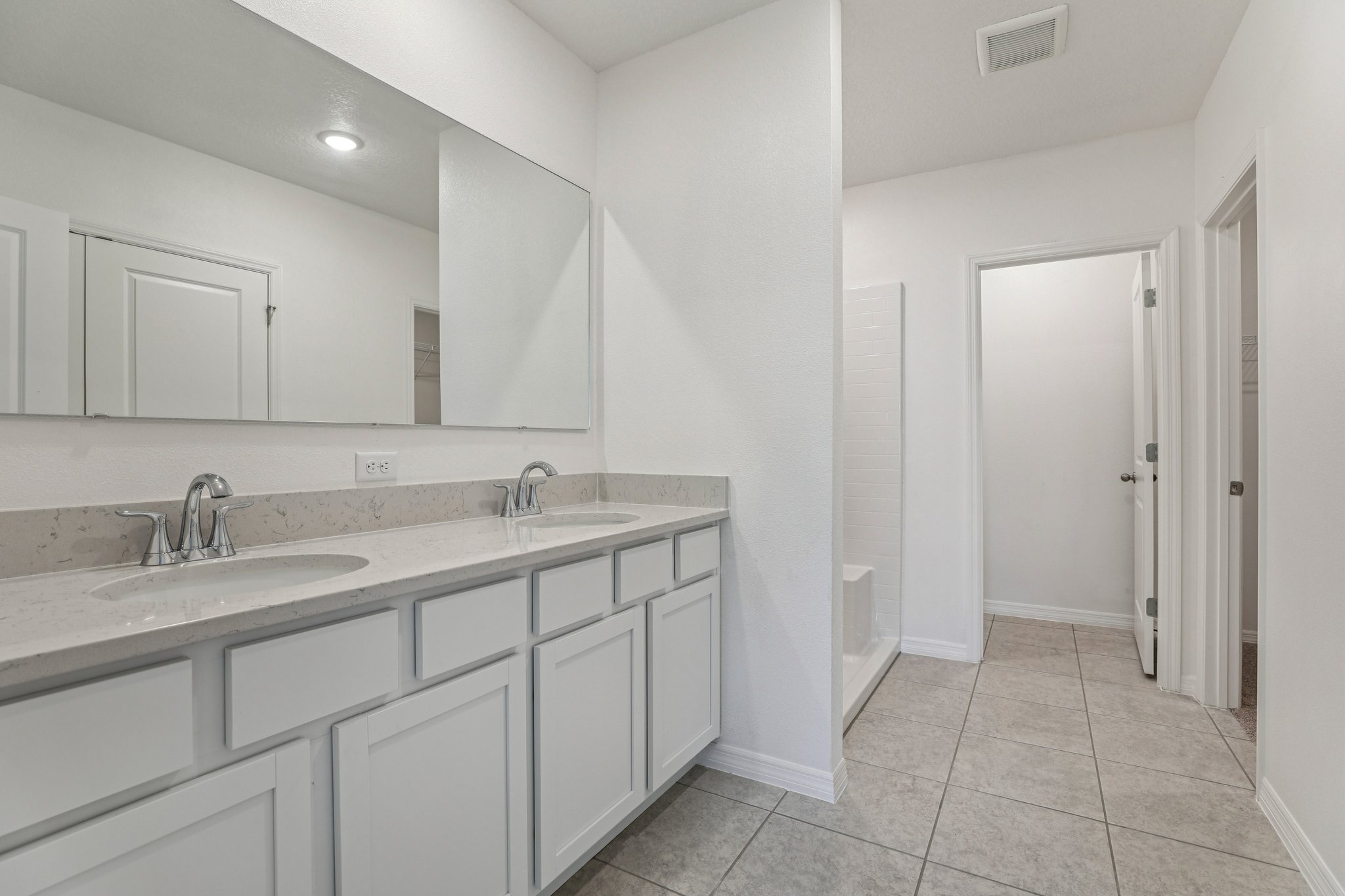 Modern bathroom with dual sinks, marble countertops, and a spacious mirror.