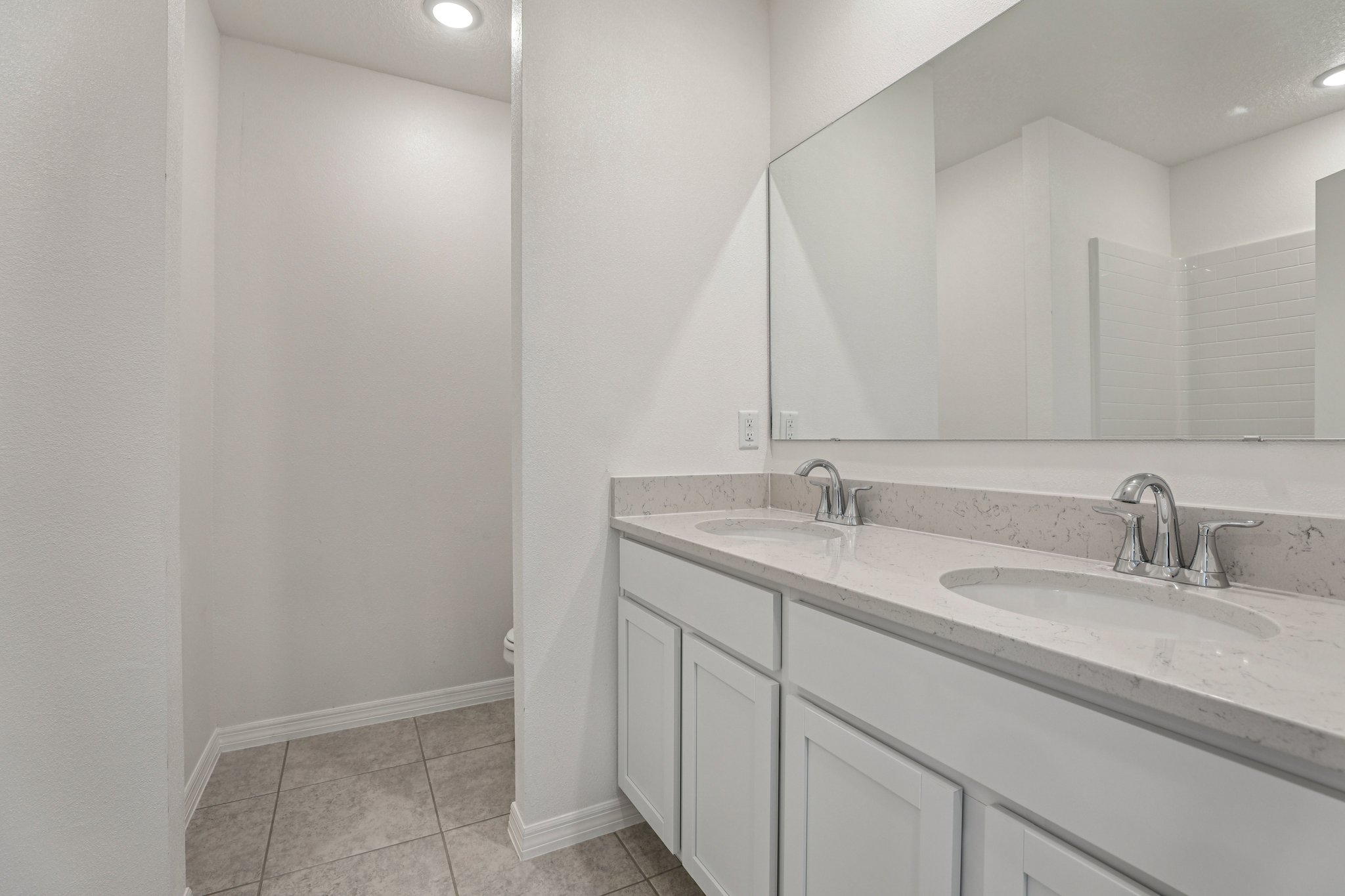 Modern bathroom featuring a double vanity with a large mirror and sleek fixtures.