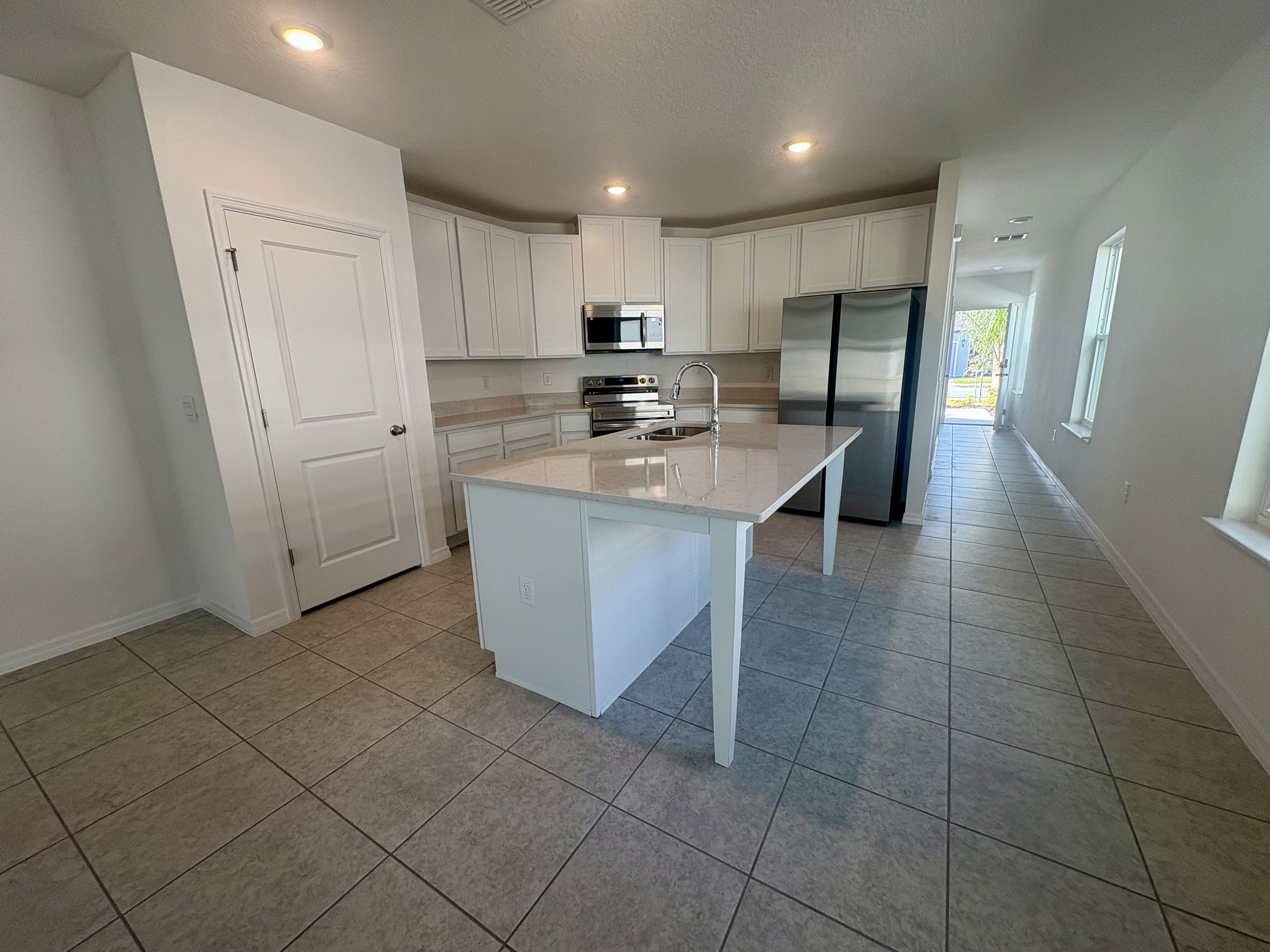 Modern kitchen with white cabinetry, stainless steel appliances, and a spacious island in a bright, open floor plan.