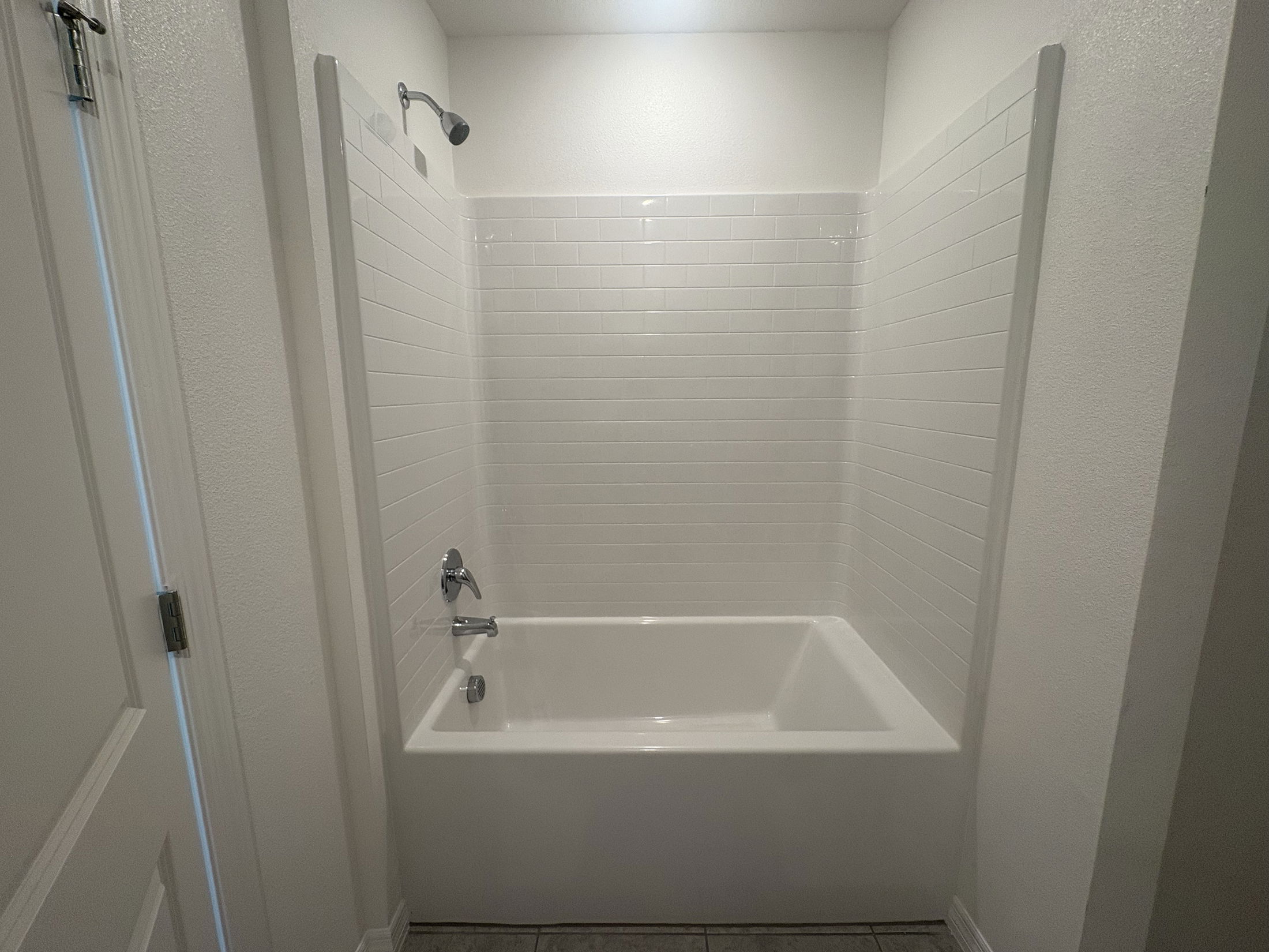 Modern bathroom featuring a clean white tile shower and bathtub combination with chrome fixtures.