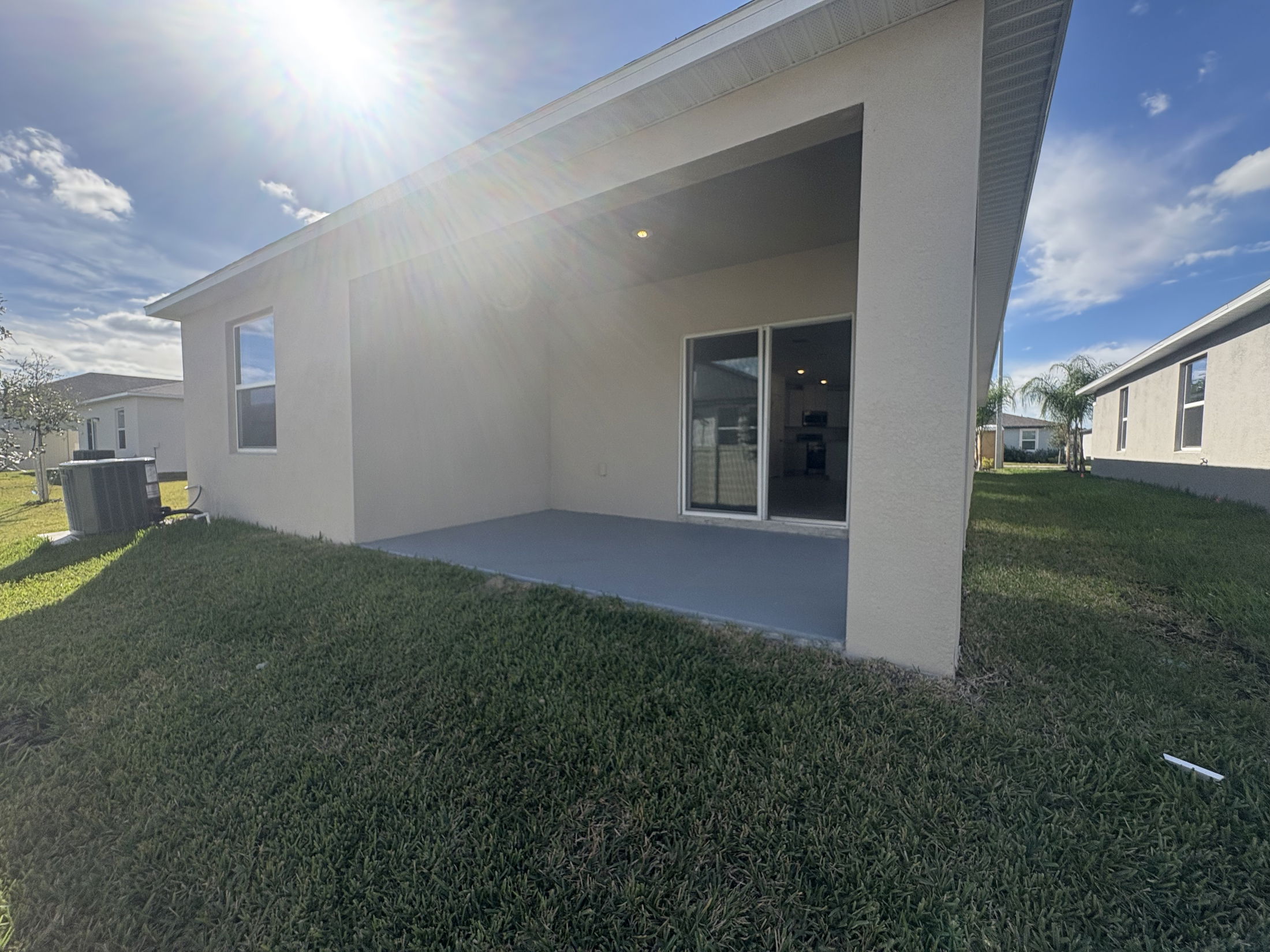 Modern suburban home with covered patio and green lawn under a sunny sky.