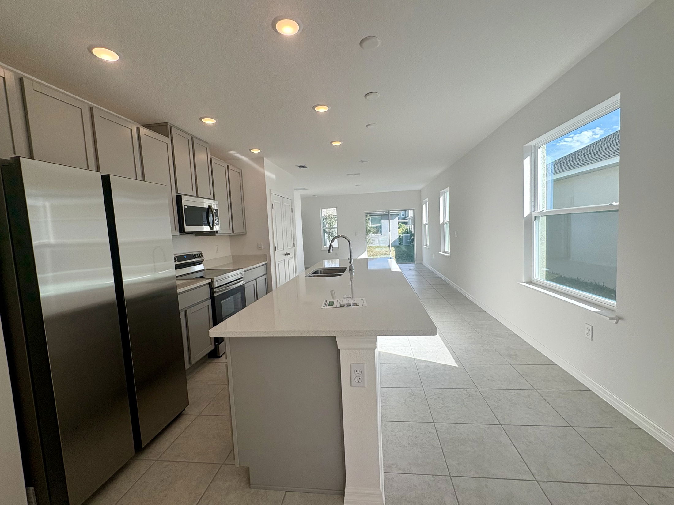 Modern kitchen with stainless steel appliances, white cabinetry, and a spacious open layout featuring abundant natural light.