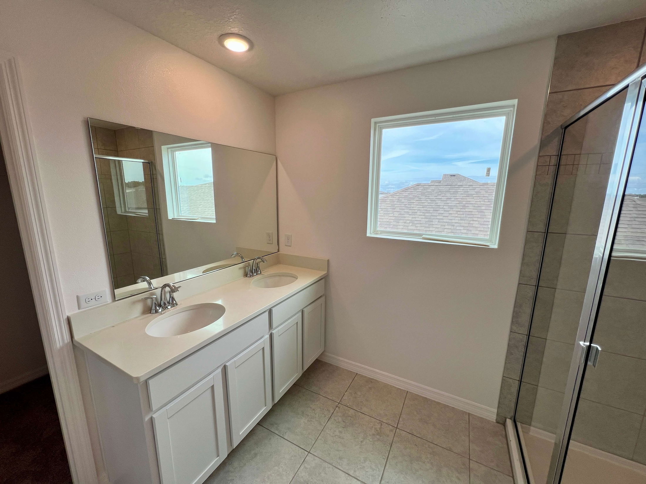 Modern bathroom with double sink vanity, large mirror, and glass shower enclosure.